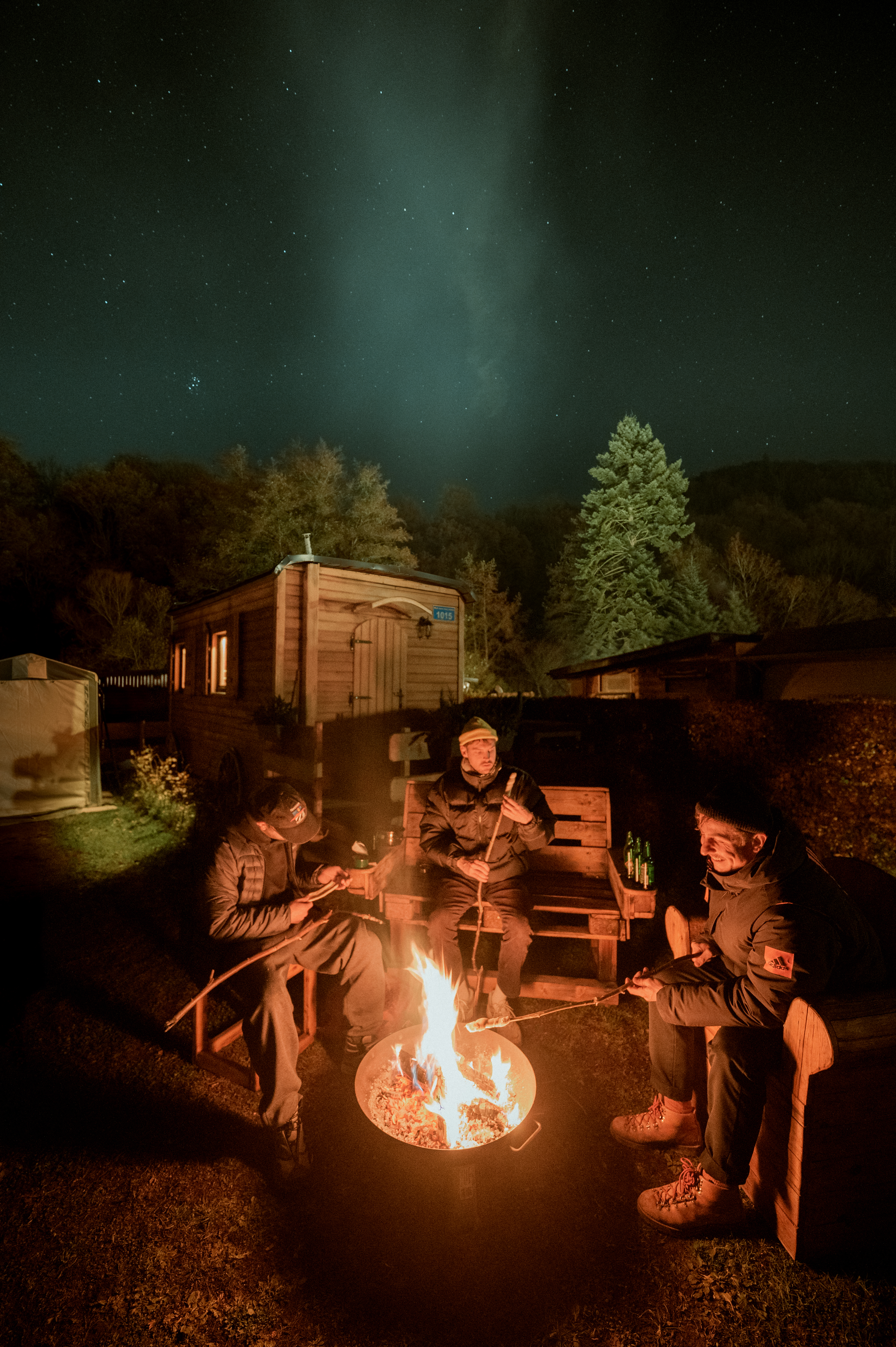 Freunde sitzen am Lagerfeuer in der Eifel