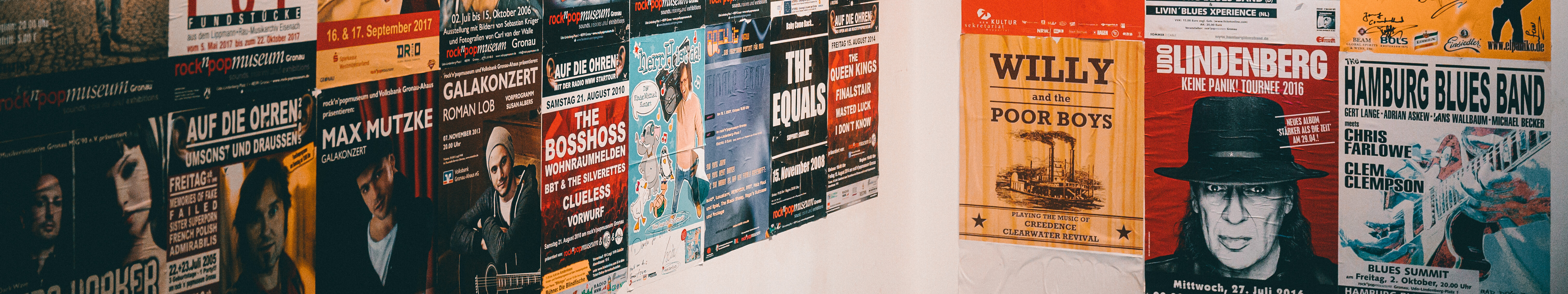 Zwei Wände, die im rock'n'popmuseum Gronau mit bunten Konzertplakaten tapeziert sind