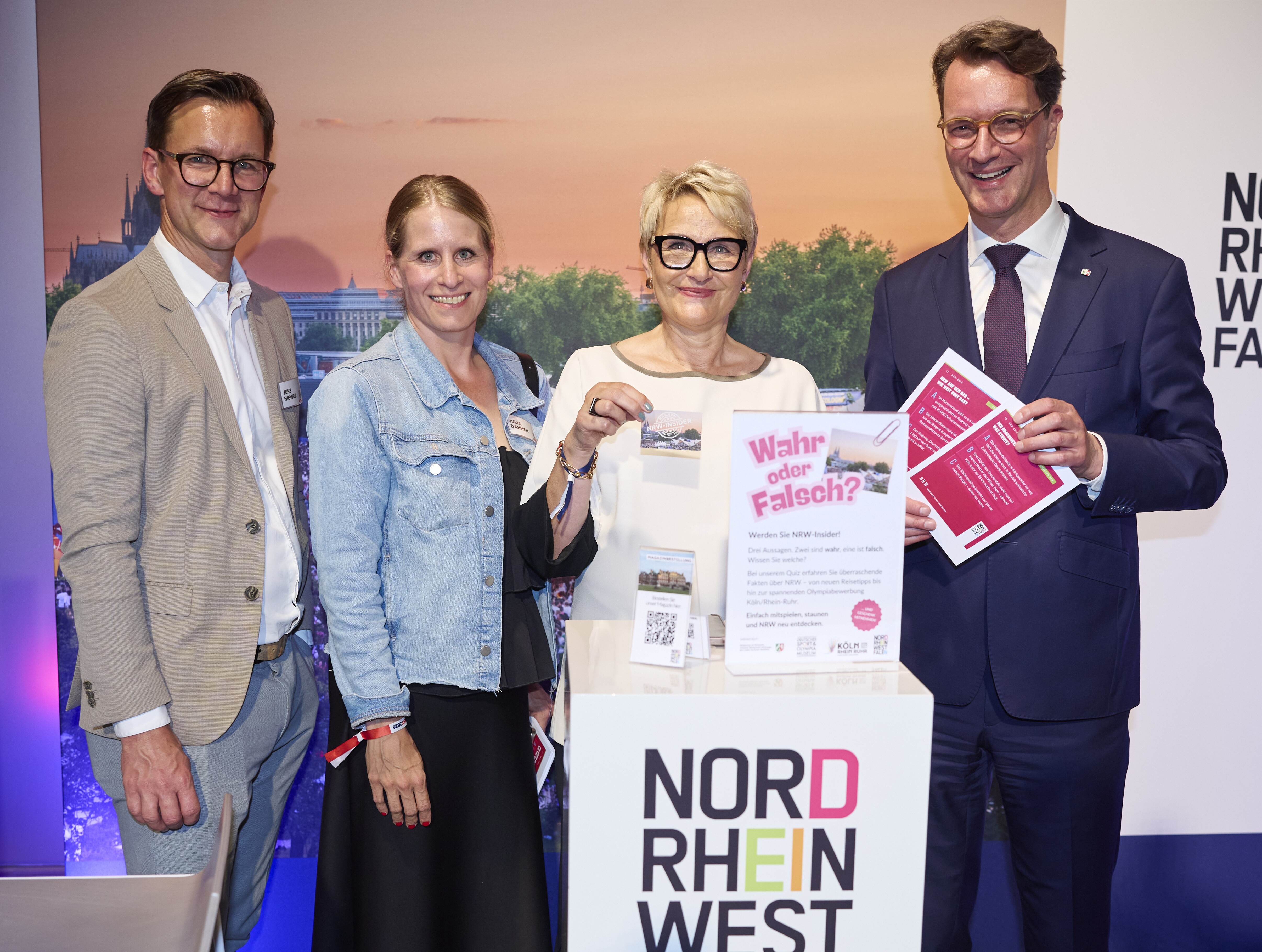 NRW-Ministerpräsident Hendrik Wüst, Vorstandsvorsitzende des Tourismus NRW, Dr. Heike Döll-König, und zwei weitere Mitarbeitende des TOurismus NRW am Tourismus-NRW-Stand auf dem NRW-Fest in der Landesvertretung in Berlin 2026.