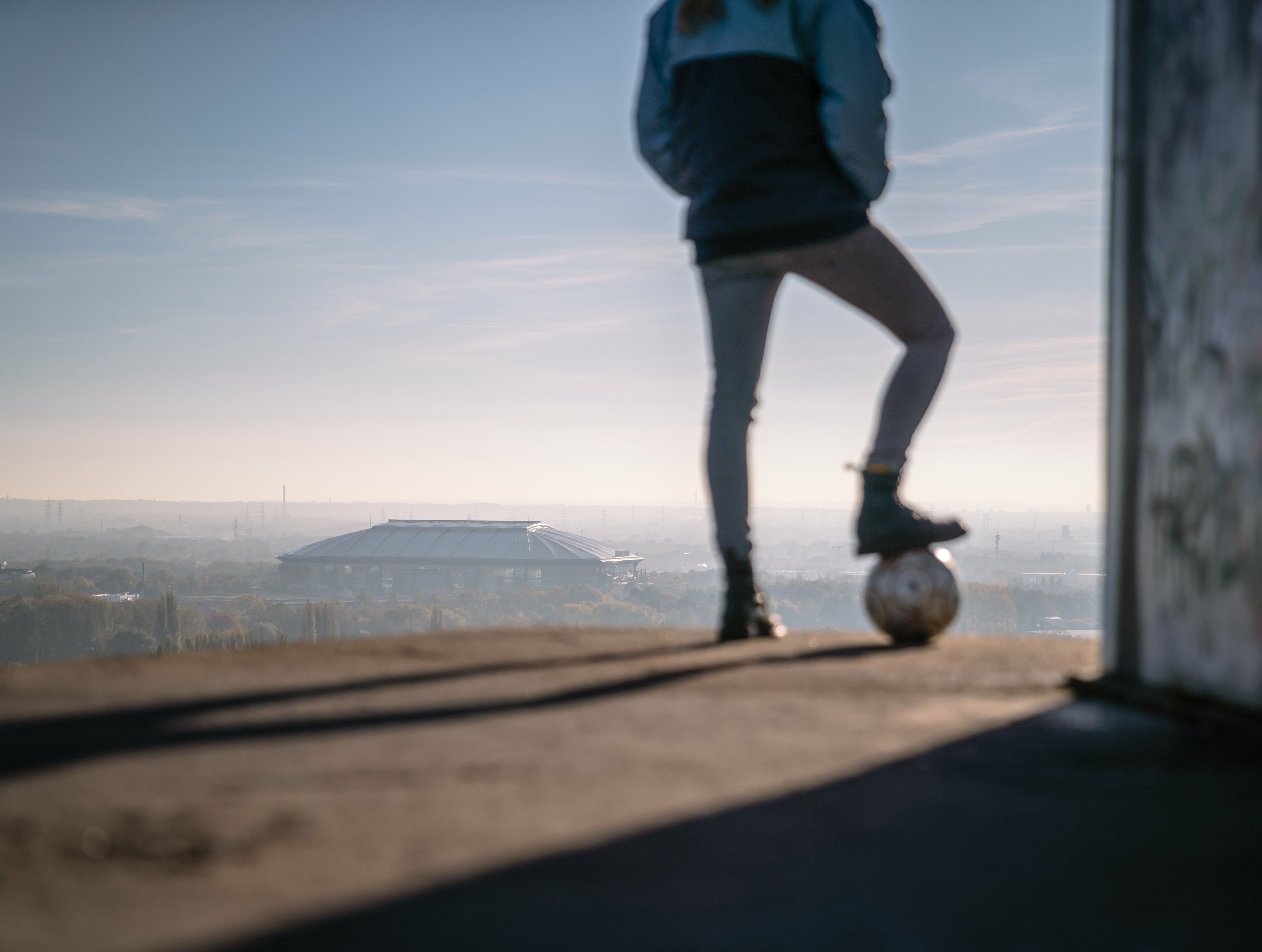 Eine Person mit einem Fußball blickt auf Halde Rheinelbe in Gelsenkirchen