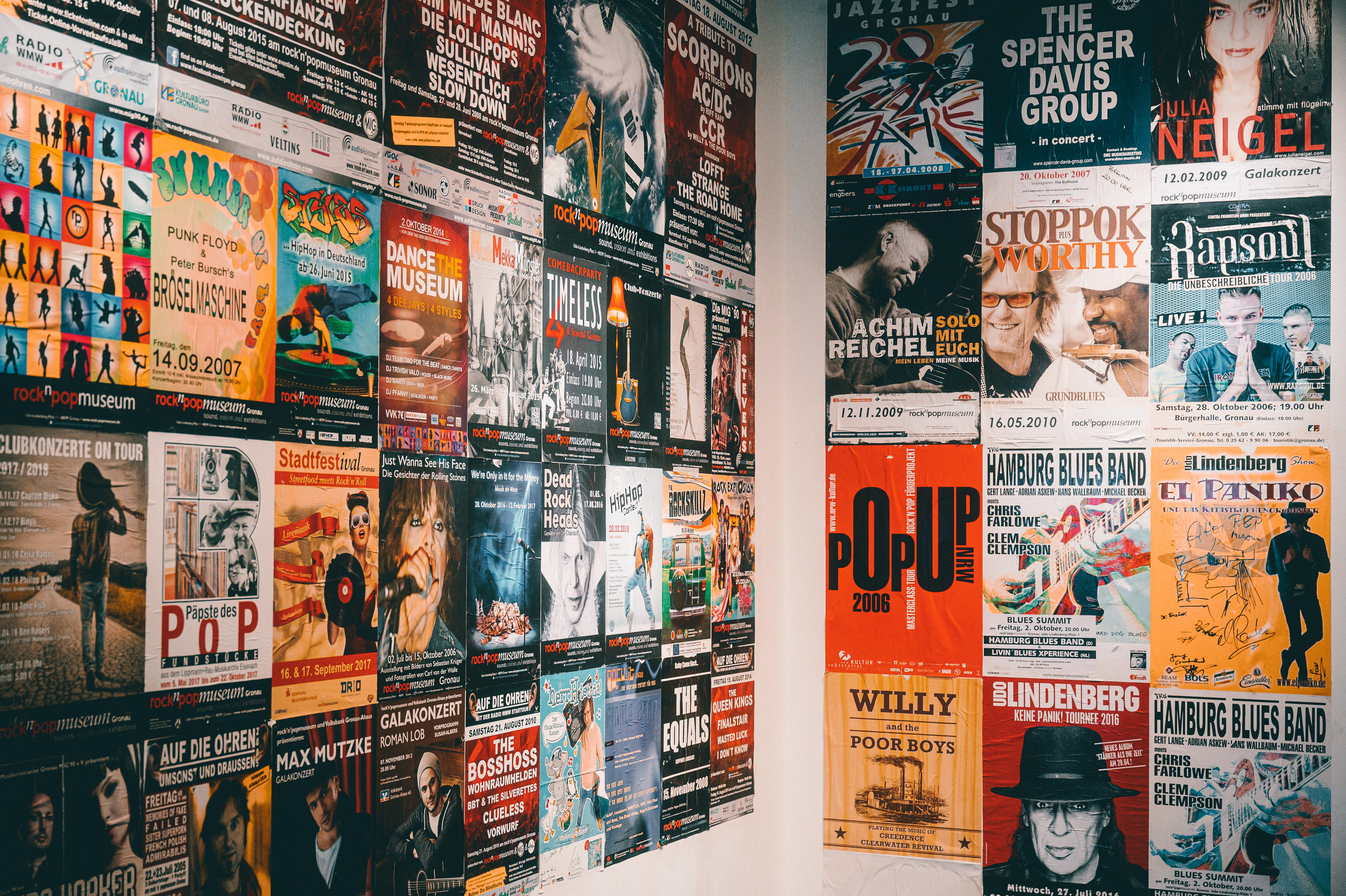 Zwei Wände, die im rock'n'popmuseum Gronau mit bunten Konzertplakaten tapeziert sind