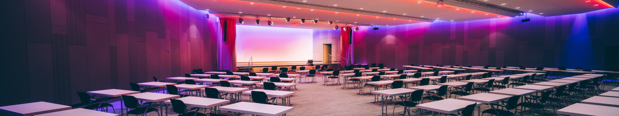 Stühle und Tische in einem lila beleuchteten Veranstaltungsraum im CCD Congress Center Düsseldorf