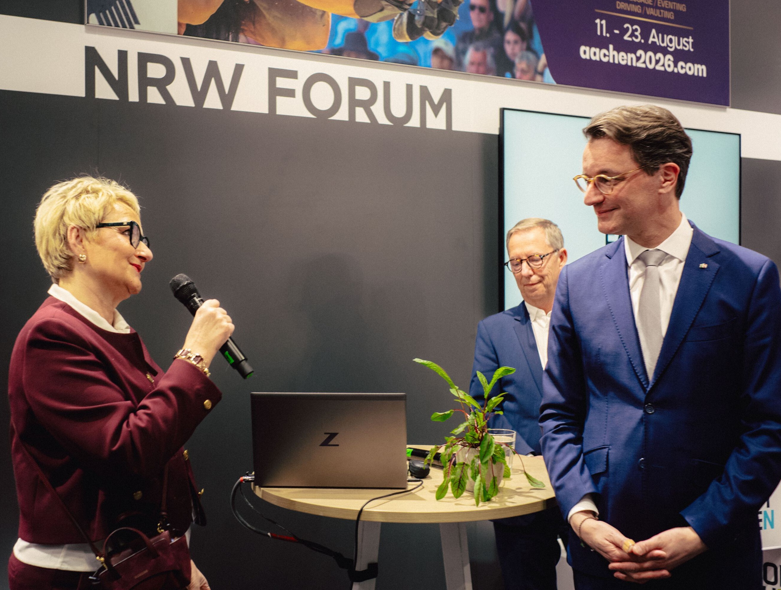 Dr. Heike Döll-König, Geschäftsführerin von Tourismus NRW, spricht auf der ITB 2026 in ein Mikrofon. NRW-Ministerpräsident Hendrik Wüst hört ihr zu.