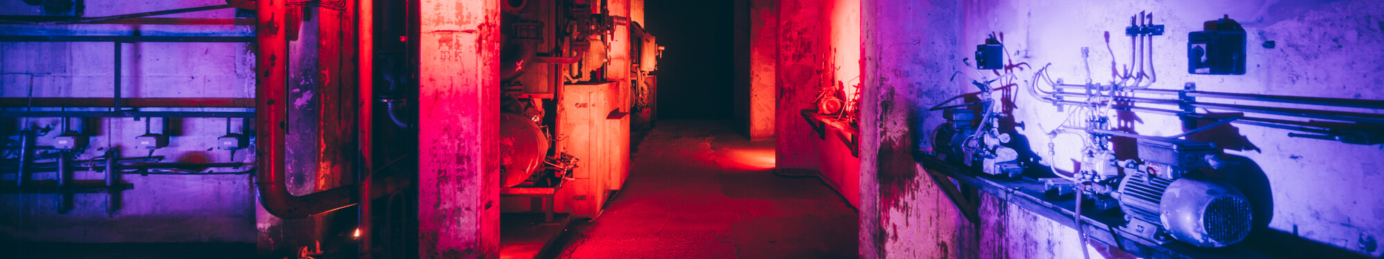 Beleuchtetes Museumsareal auf dem des Unesco-Welterbe Zollverein in Essen © Tourismus NRW e.V./Johannes Höhn Blick in die ehemalige, mit rotem und violettem Neonlicht beleuchtete Fabrikanlage des heutigen Unesco-Welterbes Zollverein in Essen.