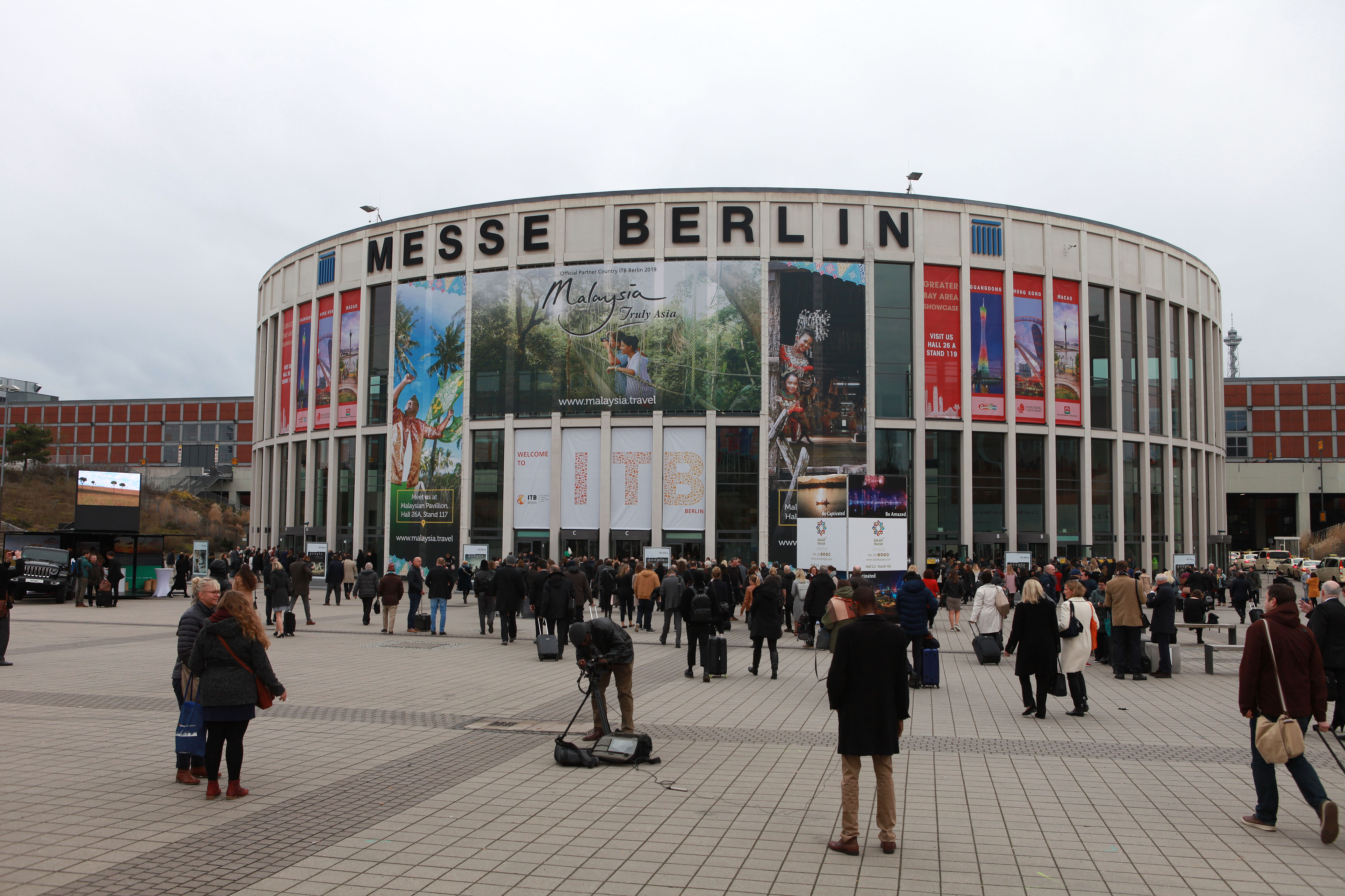 Menschen stehen vor dem Eingang der Messe Berlin, in der die ITB stattfindet.