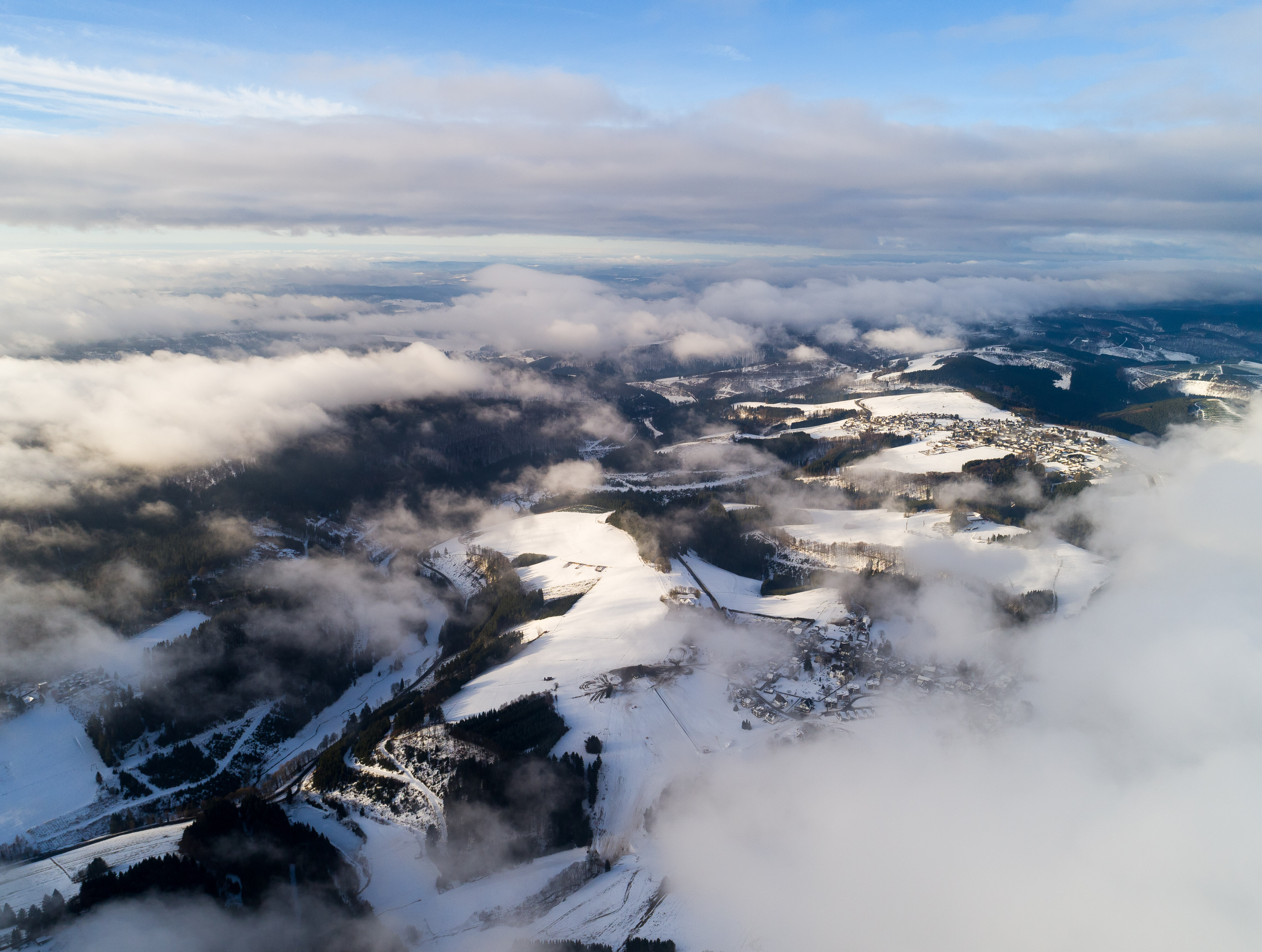 Wolken ziehen über die schneebedeckten Berge am Kahlen Asten bei Winterberg im Sauerland. 