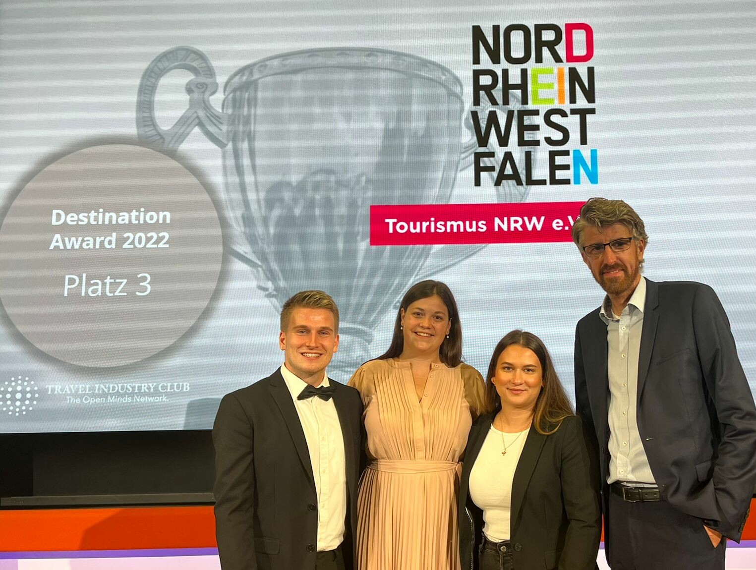Mitarbeitende des Tourismus NRW vor einem Bildschirm, auf dem steht "Destination Award 2022 - Platz 3"