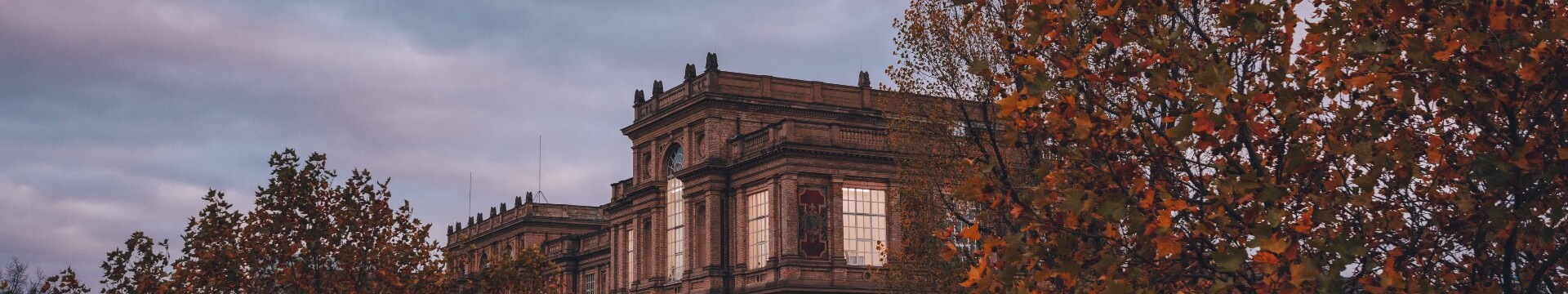 Das historische Gebäude der Kunstakademie Düsseldorf hinter herbstlich gefärbten Bäumen