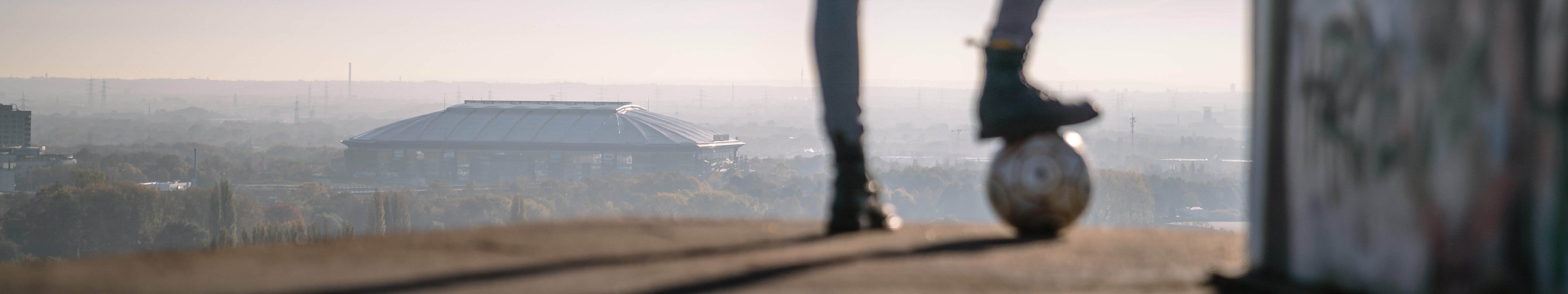 Eine Person mit einem Fußball blickt auf Halde Rungenberg in Gelsenkirchen