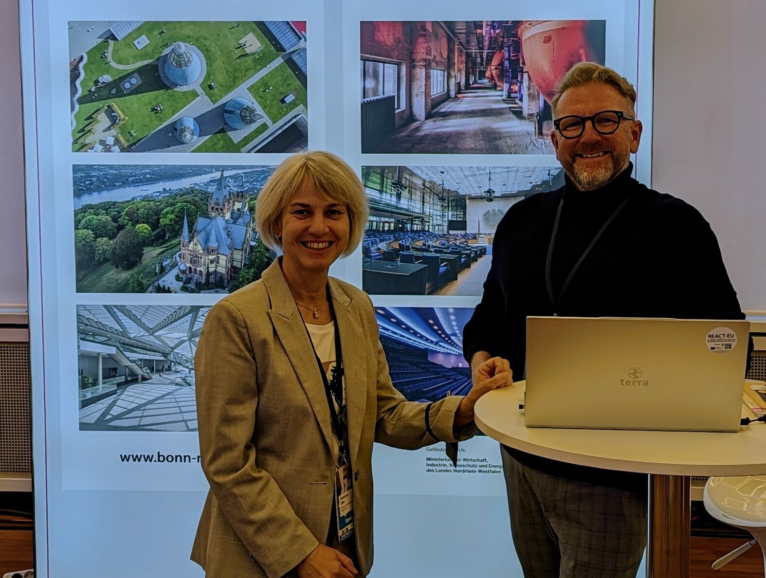 Verbändekongress 2022 in Berlin © Tourismus NRW e.V. Ein Mann und eine Frau stehen vor einem Plakat zum Tagungsland NRW und zur Region Bonn.