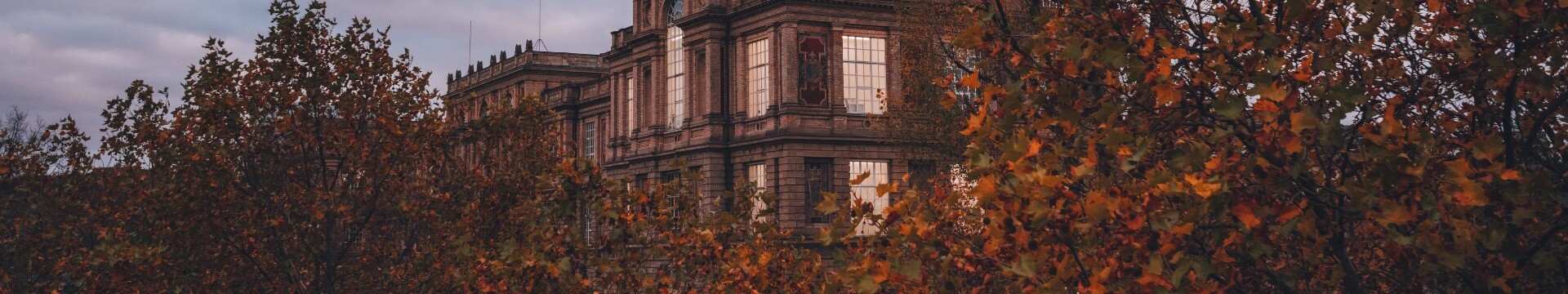 Das historische Gebäude der Kunstakademie Düsseldorf hinter herbstlich gefärbten Bäumen