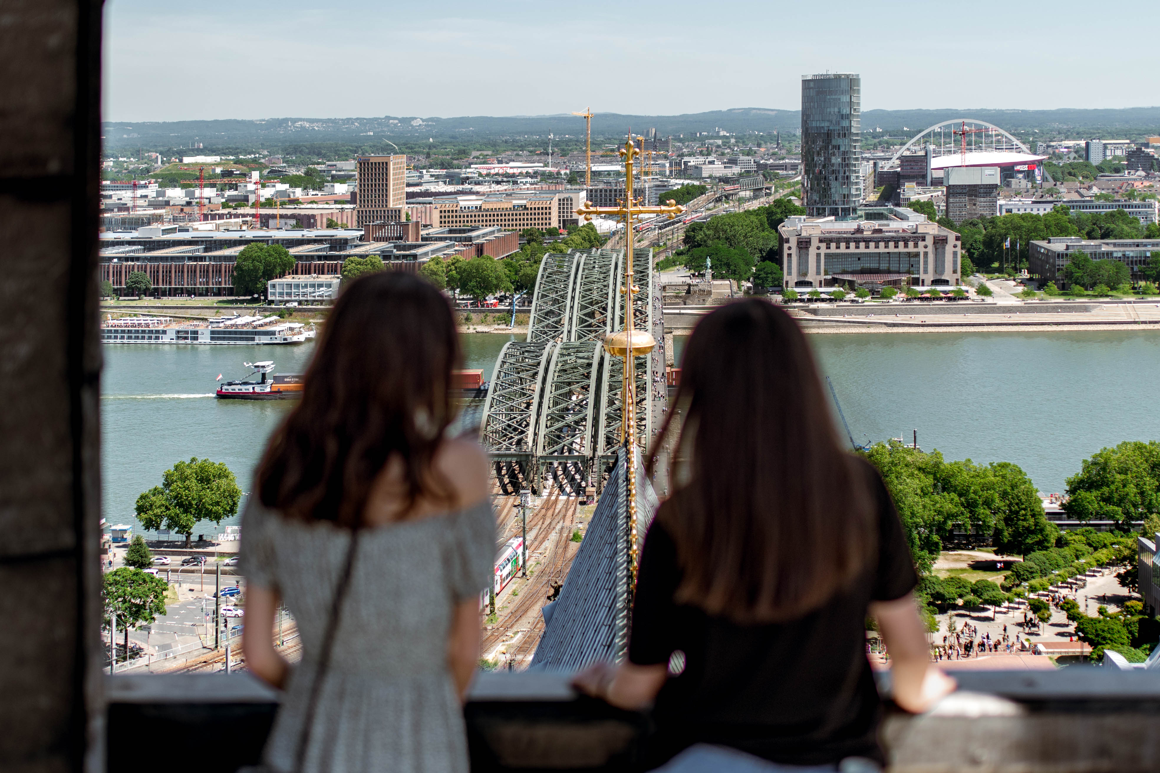 Zwei Menschen schauen von oben auf die Hohenzollernbrücke in Köln