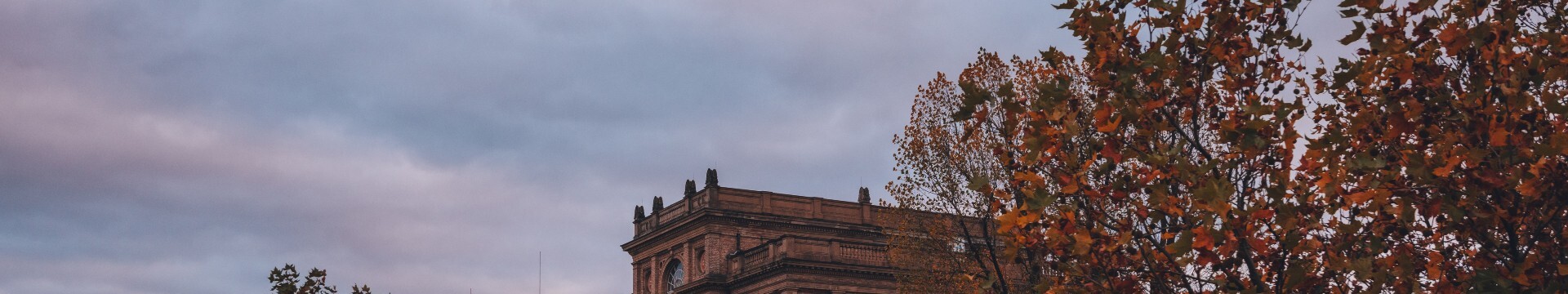 Das historische Gebäude der Kunstakademie Düsseldorf hinter herbstlich gefärbten Bäumen
