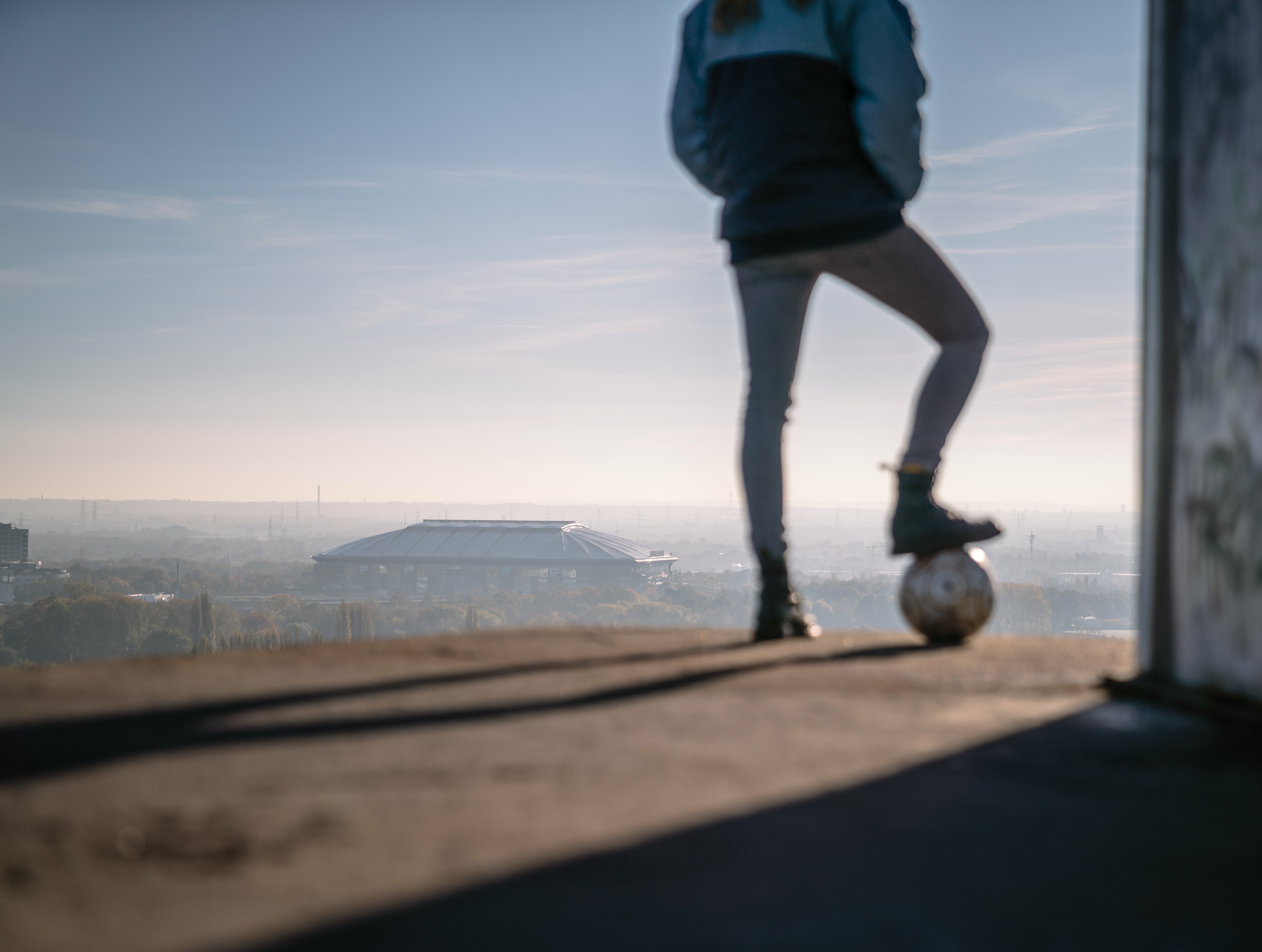 Eine Person mit einem Fußball blickt auf Halde Rheinelbe in Gelsenkirchen