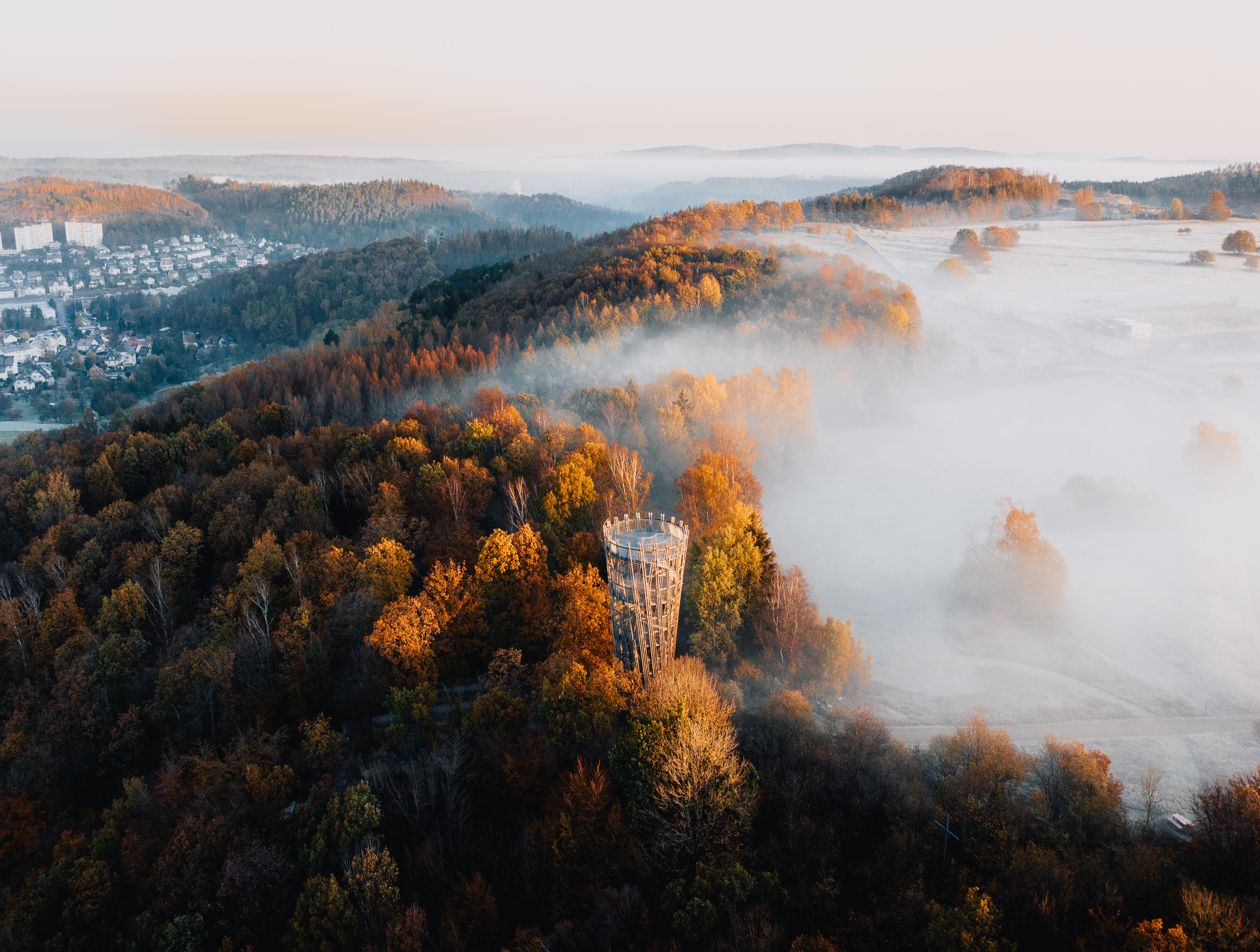 Nebelschwaden im herbstlich gefärbtem Wald am hölzernen Jübergturm im Sauerland  