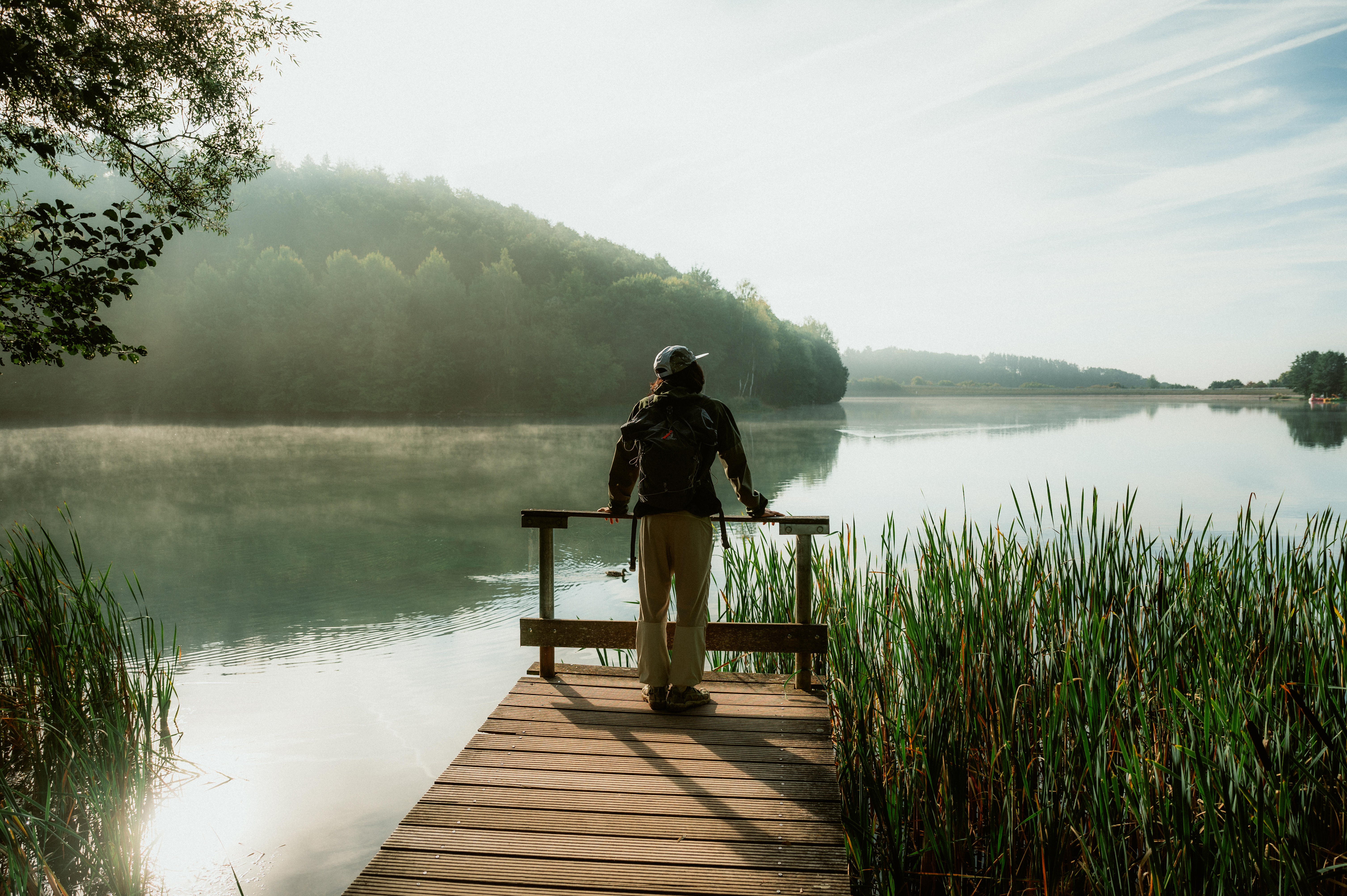 Person steht auf einem Holzsteg am Freilinger See in Blankenheim in der Eifel