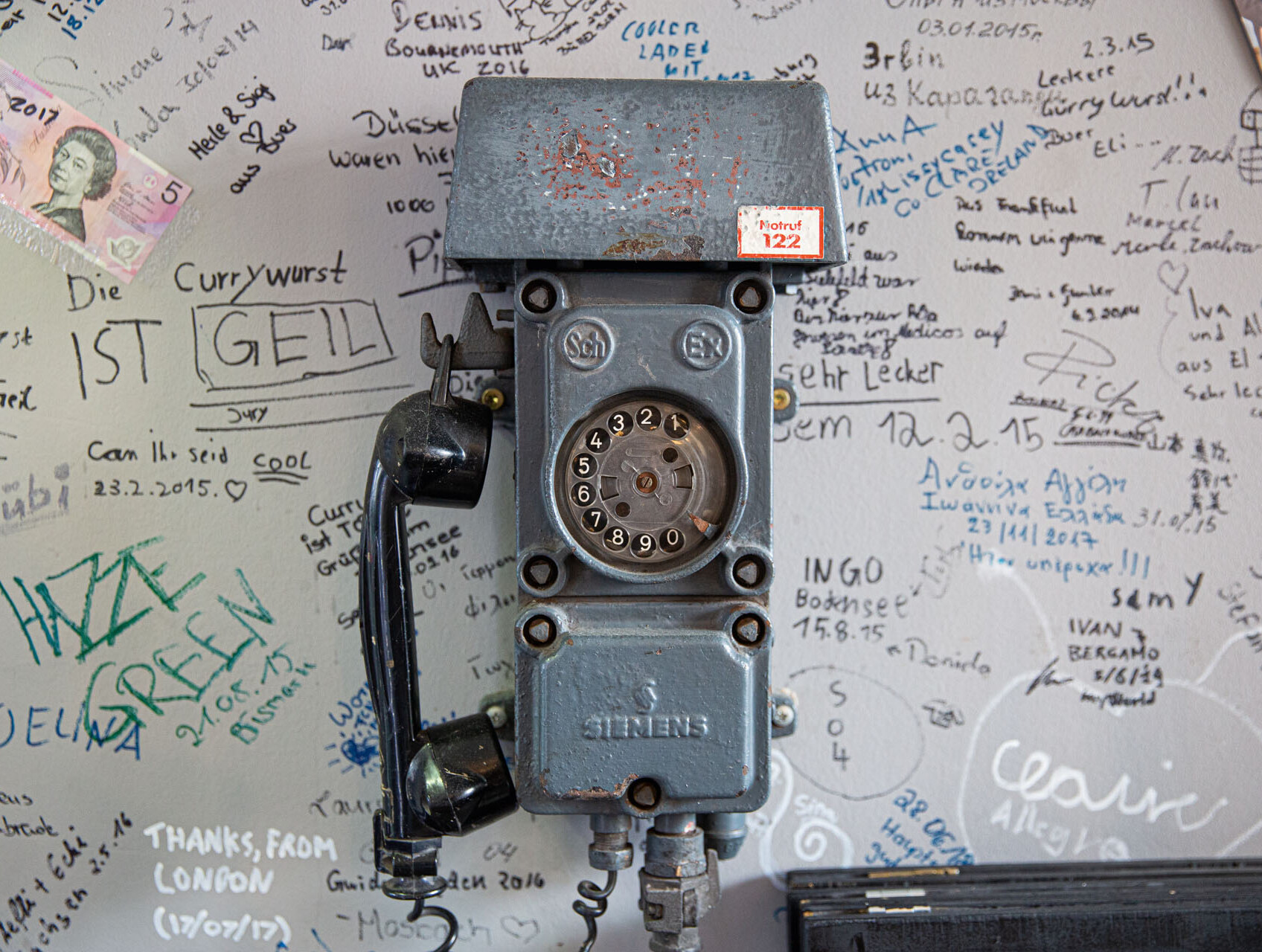 Ein historisches Bergwerkstelefon hängt bei Curry Heinz in Gelsenkirchen an einer Wand mit zahlreichen handgeschriebenen Kommentaren und Grüßen aus aller Welt. © Tourismus NRW e.V./Holger Hage