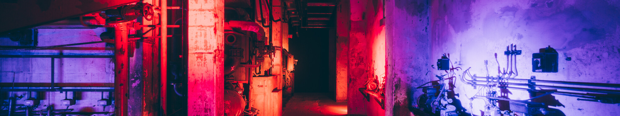 Blick in die ehemalige, mit rotem und violettem Neonlicht beleuchtete Fabrikanlage des heutigen Unesco-Welterbes Zollverein in Essen. 