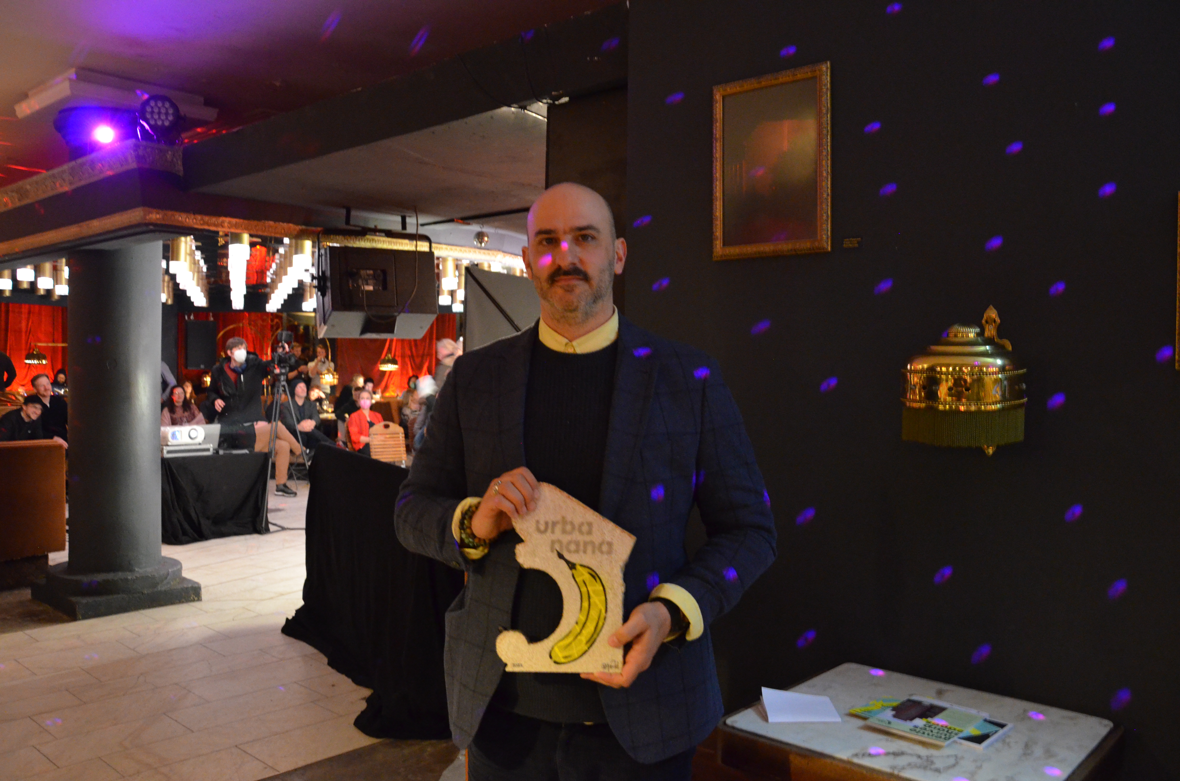 Der Macher der App EcoHopper, die zu nachhaltigen Geschäften und Einrichtungen führt, hält einen vom Kölner Künstler Thomas Baumgärtel gestalteten urbanana-Award in der Hand. 