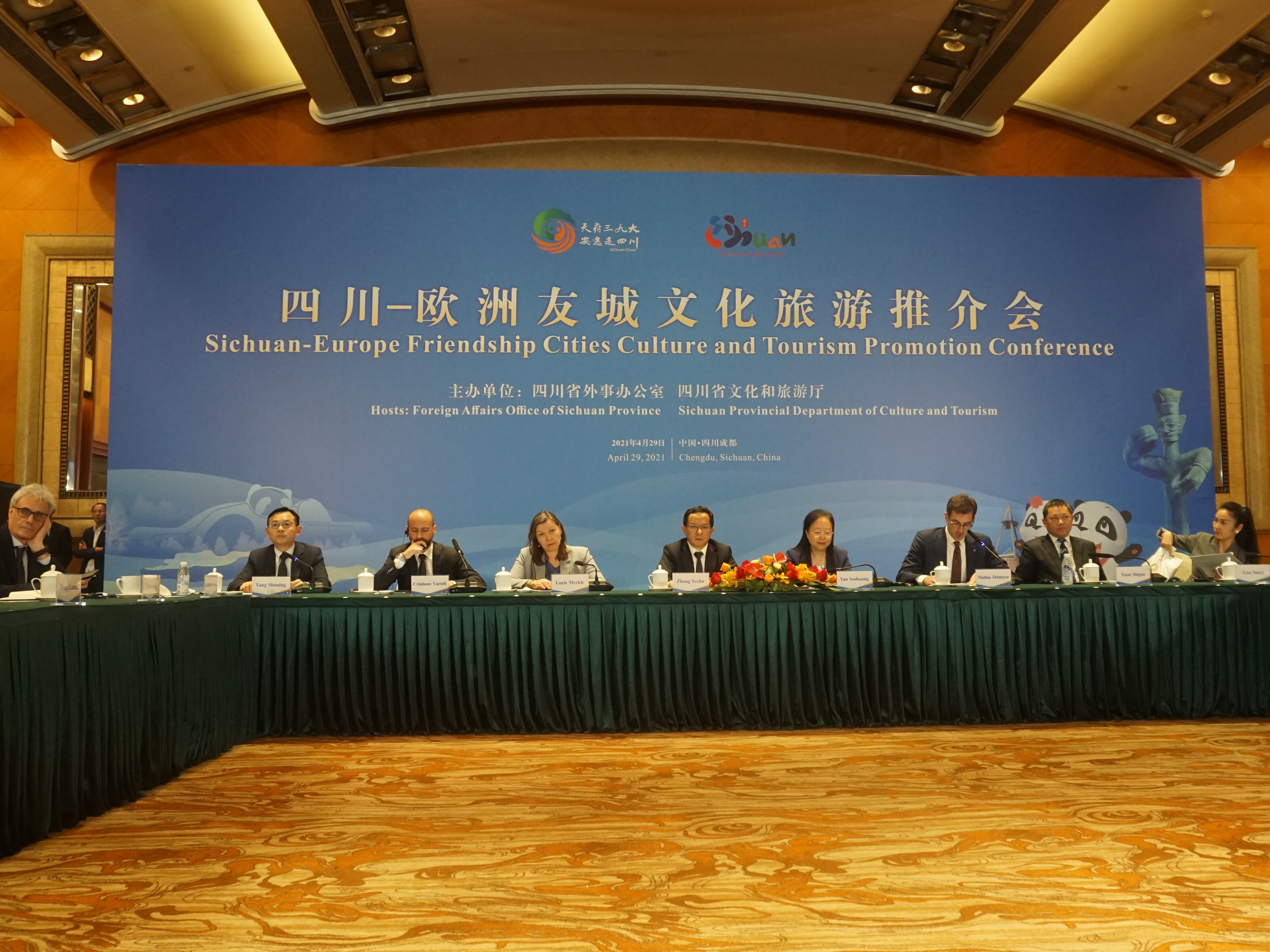 Teilnehmende einer hybriden Tourismuskonferenz in Sichuan sitzen an einem großen Tisch.