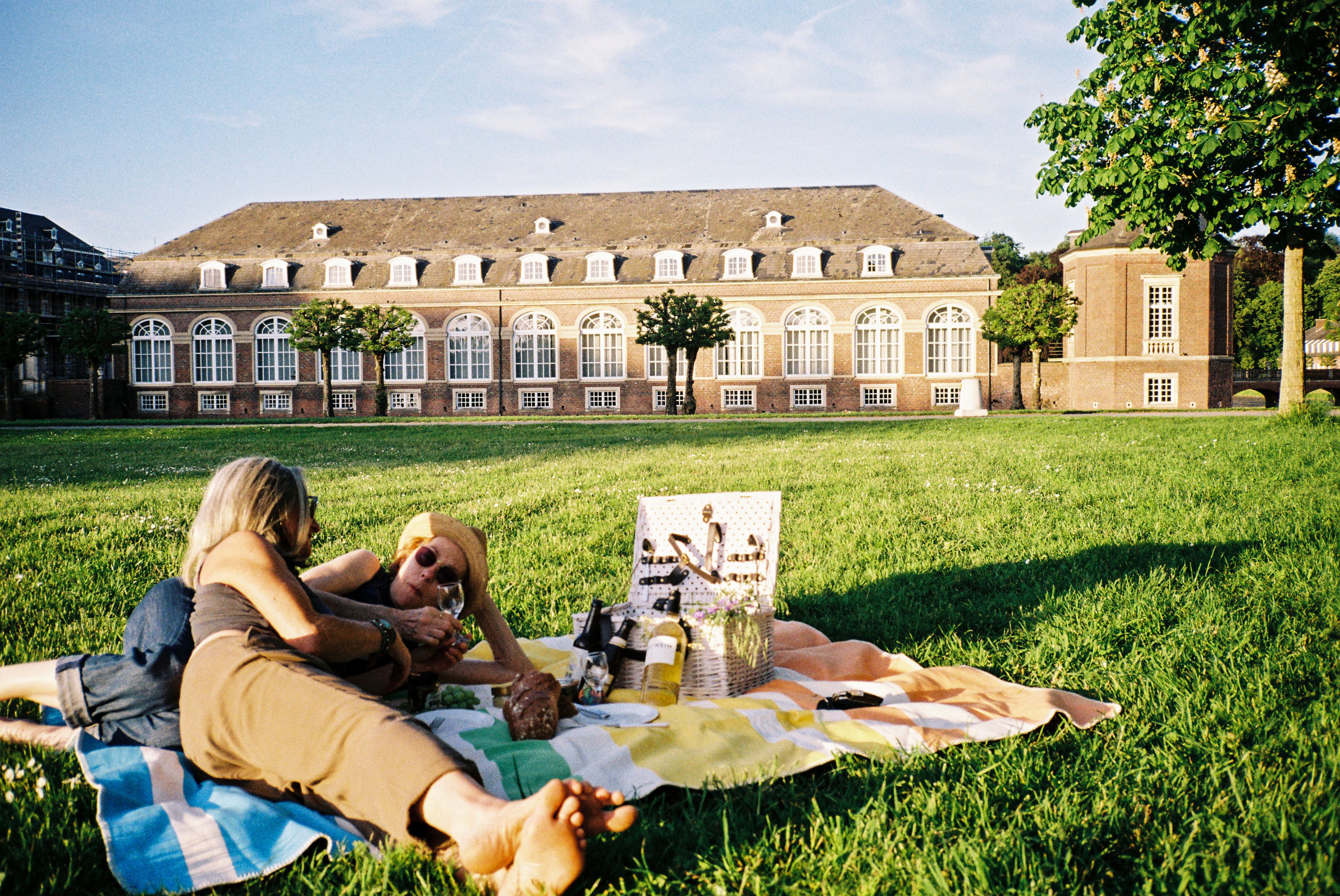 Picknick am Schloss Nordkirchen © Molle & Korn/Henri Schade Zwei Frauen liegen auf einer Picknickdecke am Schloss Nordkirchen im Münsterland.