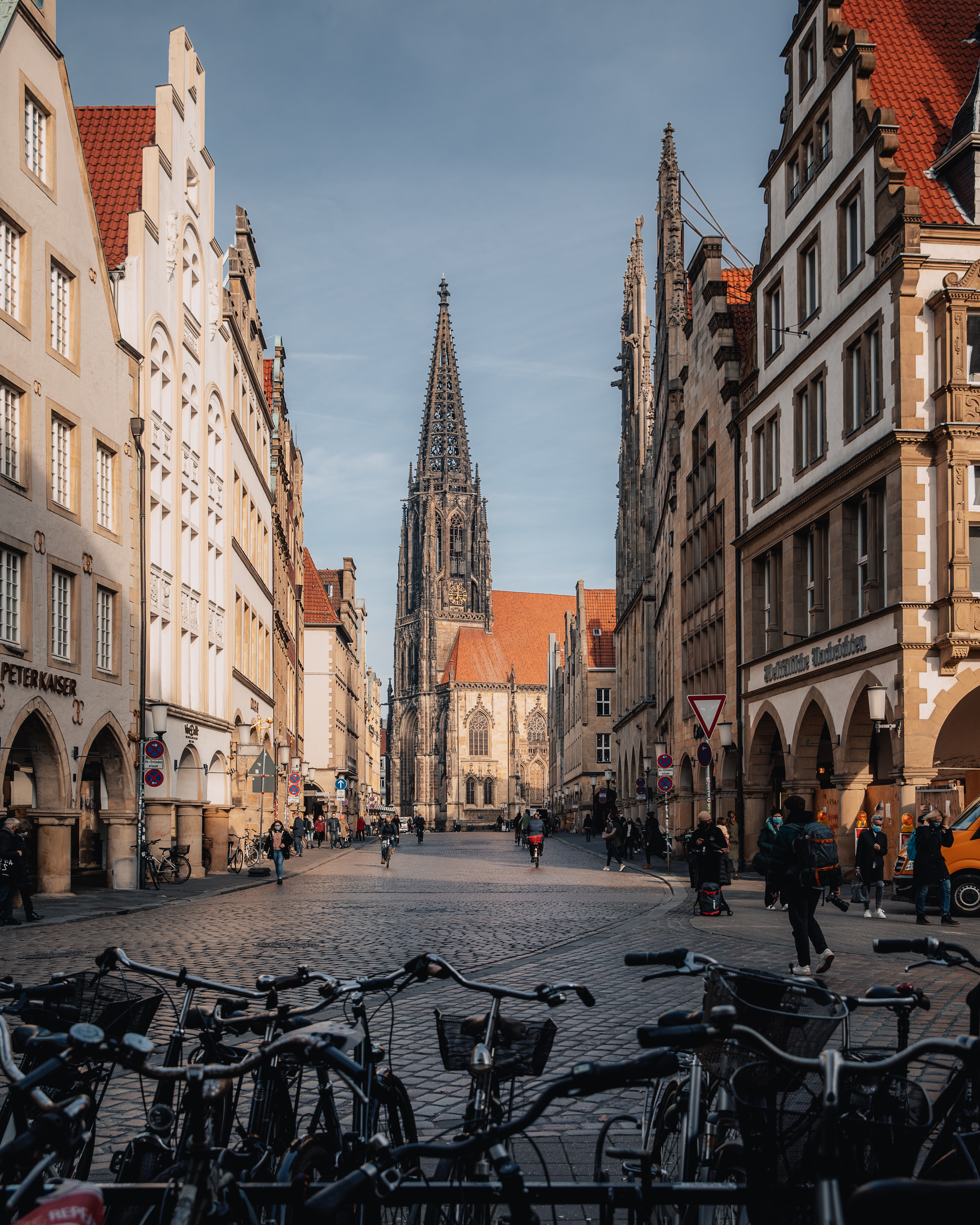 Blick auf den Prinzipalmarkt und die Lamberti-Kirche in Münster. Durch die Straße fahren viele Radfahrer.  