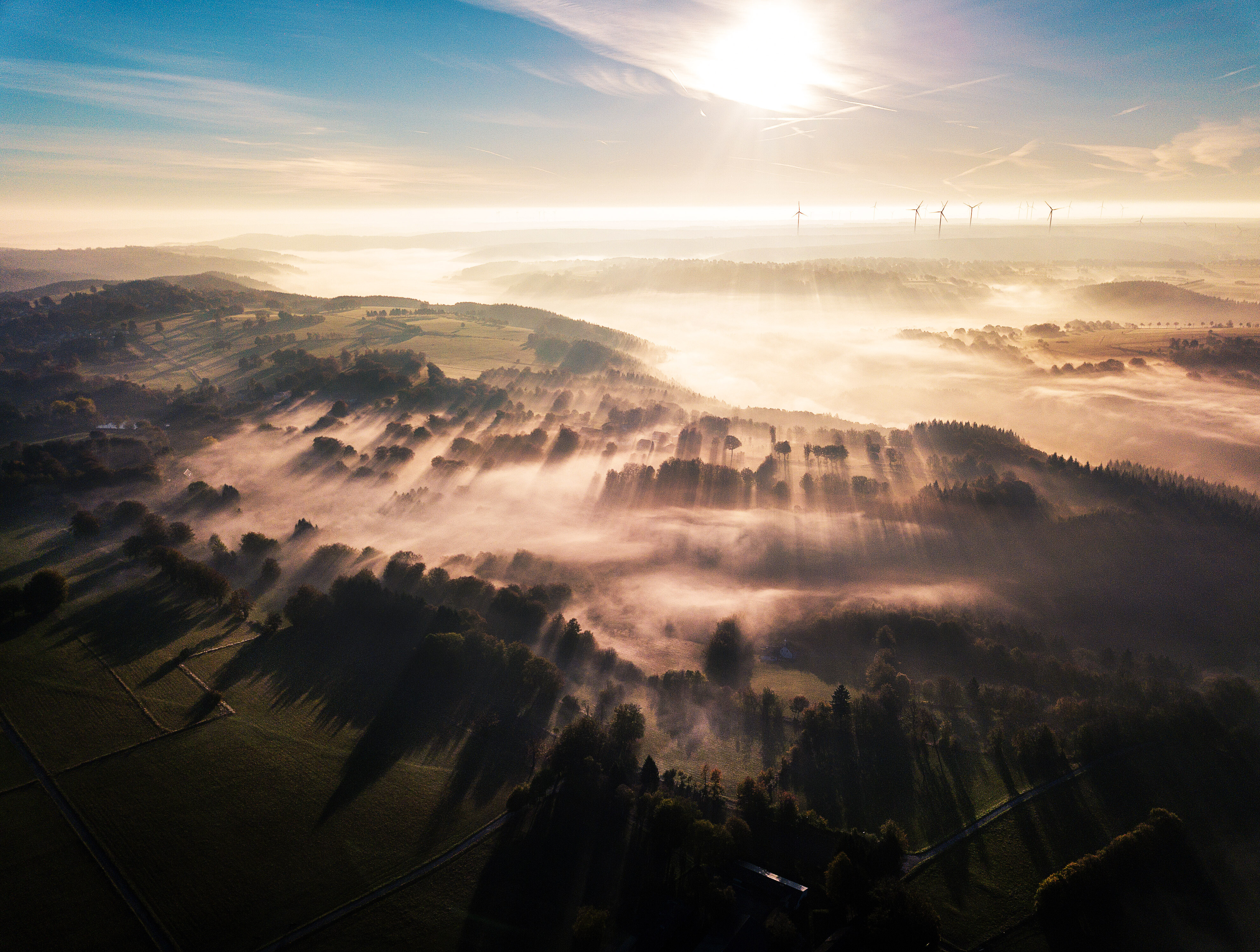 Bei Sonnenaufgang liegt Nebel über den Feldern und Wäldern der Eifel. © Tourismus NRW e.V.
