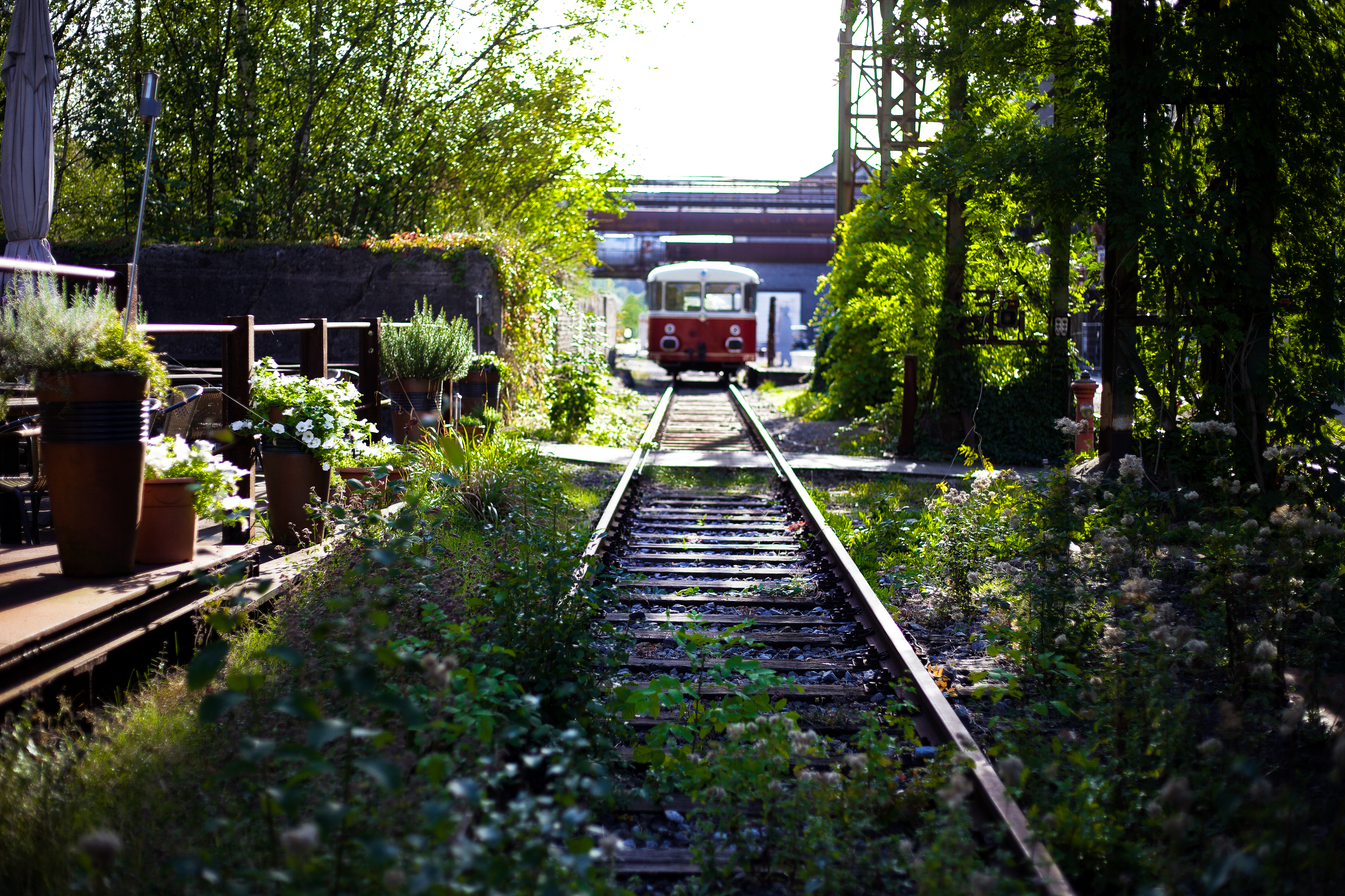 Ein alter Eisenbahnwaggon fährt auf den Gleisen durch die begrünte Außenanlage des LWL-Industriemuseums Henrichshütte in Hattingen. 