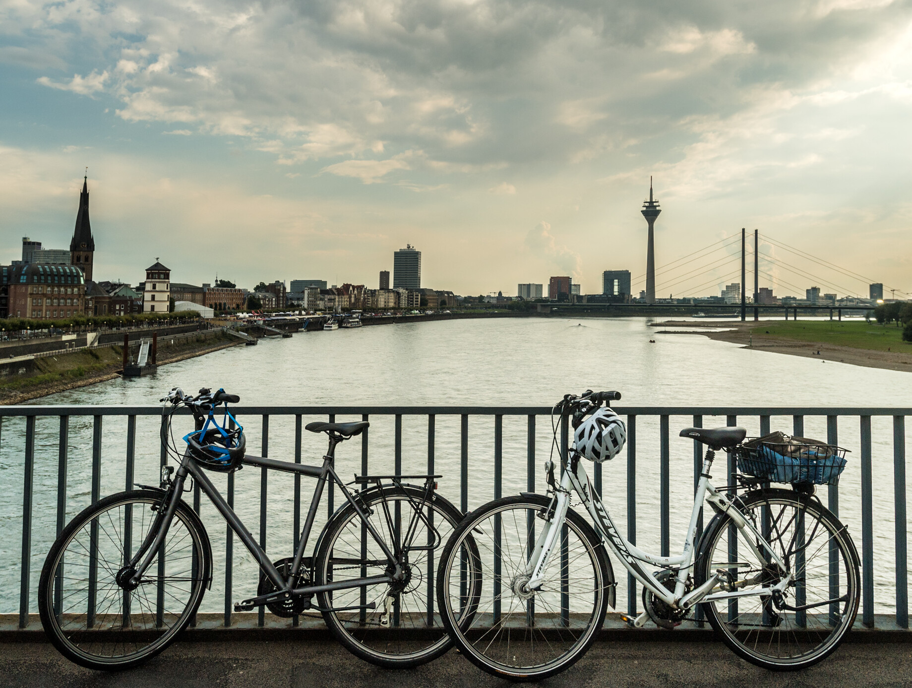 Blick auf die Skyline von Düsseldorf mit Rheinturm. Im Vordergrund stehen zwei Fahrräder auf einer Brücke über den Rhein. © Tourismus NRW e.V./Dominik Ketz