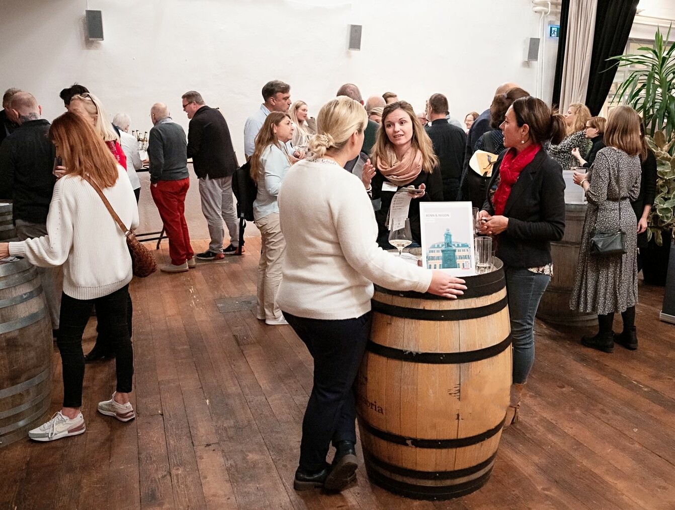 Teilnehmende beim Jahresabschlussevent der DZT Schweiz 2022 © J. Frei/DZT Schweiz 2022 Menschen stehen an Tischen und Bierfässern und unterhalten sich beim Jahresabschlussevent der DZT Schweiz 2022.