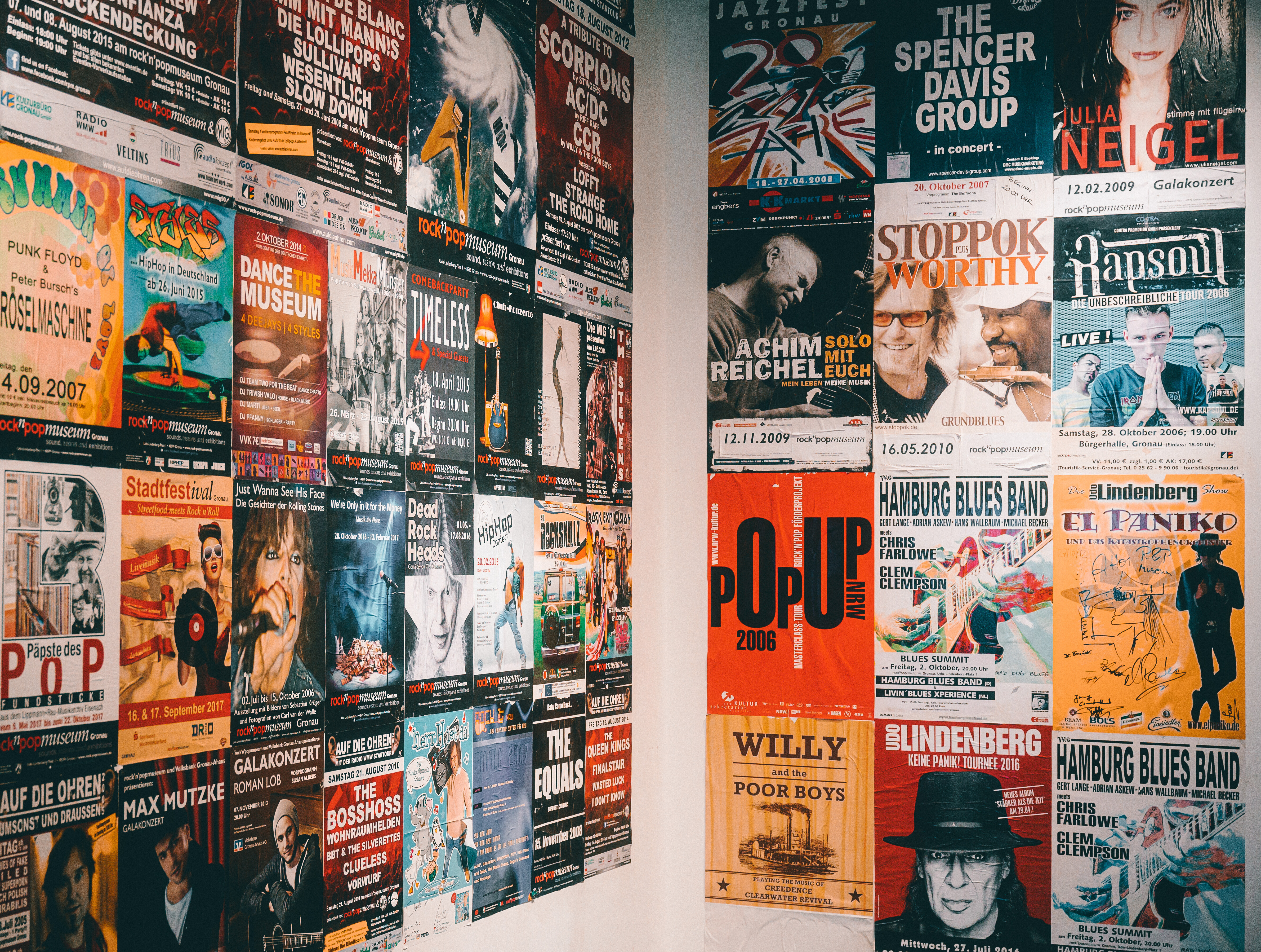 Zwei Wände, die im rock'n'popmuseum Gronau mit bunten Konzertplakaten tapeziert sind