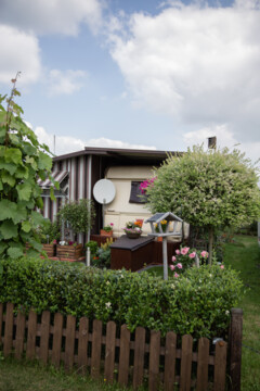 Wohnwagen steht in einem kleinen Garten im Campingpark Kerstgenshof am Niederrhein