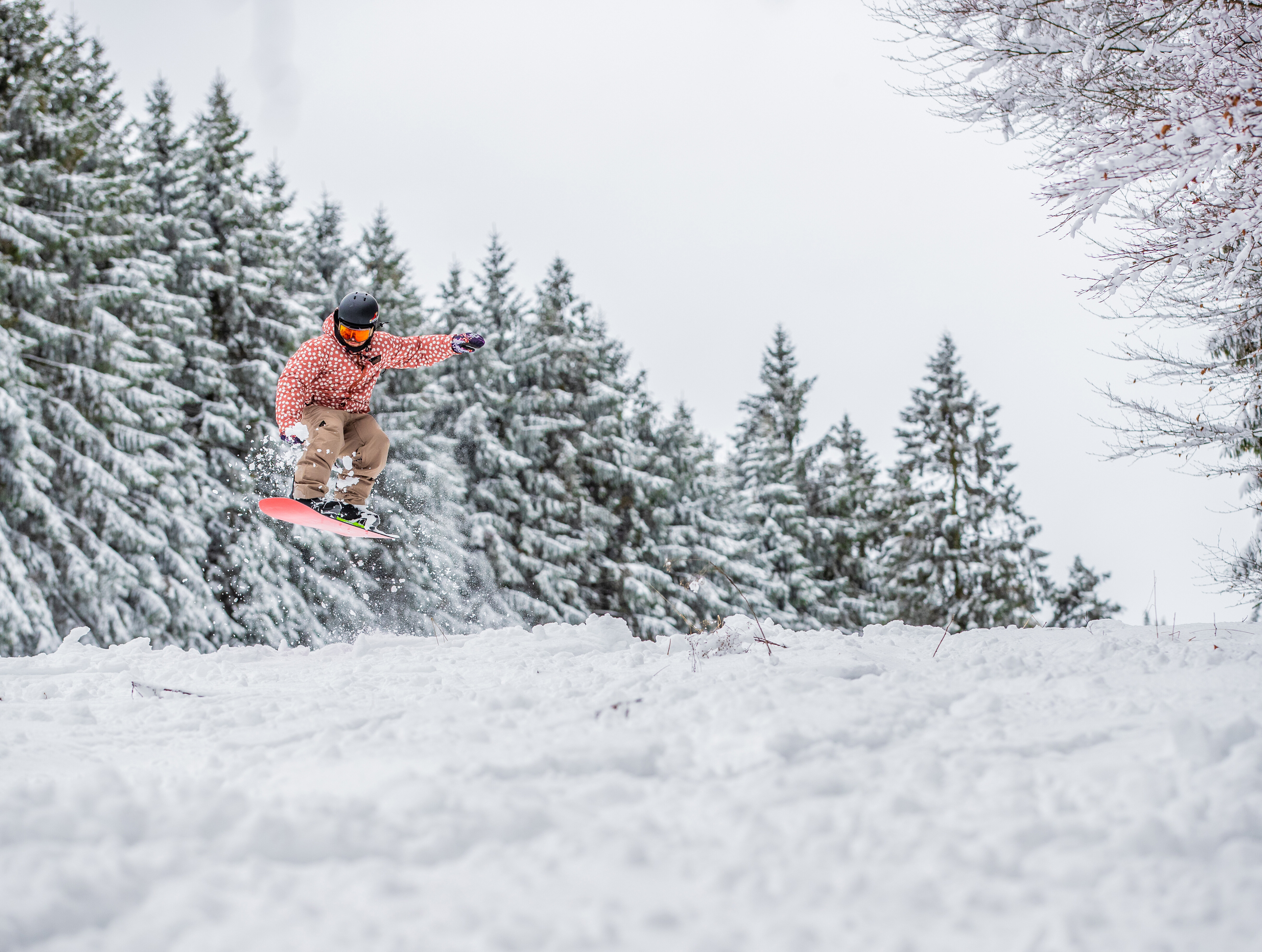 Ein Snowboardfahrer springt im Skikarussell Altastenberg über einen schneebedeckten Hügel. 