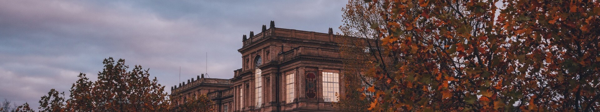 Das historische Gebäude der Kunstakademie Düsseldorf hinter herbstlich gefärbten Bäumen