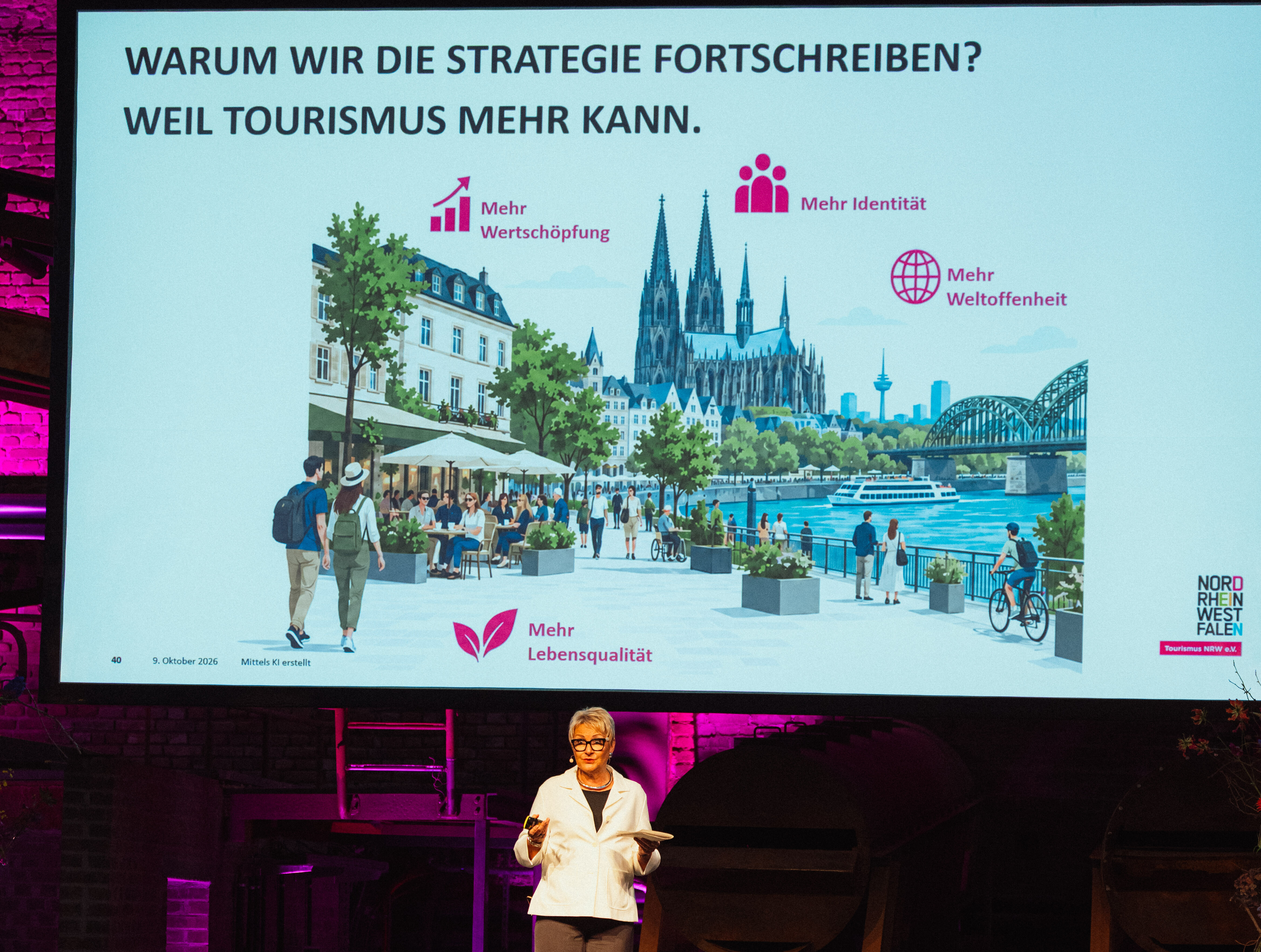 Dr. Heike Döll-König beim Tourismustag NRW x Ruhrgebiet 2026 © Tourismus NRW e.V./Thomas Kaup Dr. Heike Döll-König, Vorstandsvorsitzende von Tourismus NRW, spricht beim Tourismustag NRW x Ruhrgebiet 2026 in Dortmund vor einer Präsentationsfolie, auf der steht: "Warum wir die Strategie fortschreiben? Weil Tourismus mehr kann."