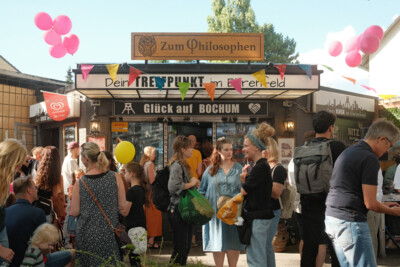 Viele Menschen stehen am Tag der Trinkhallen 2022 vor einer geschmückten Trinkhalle in Bochum.