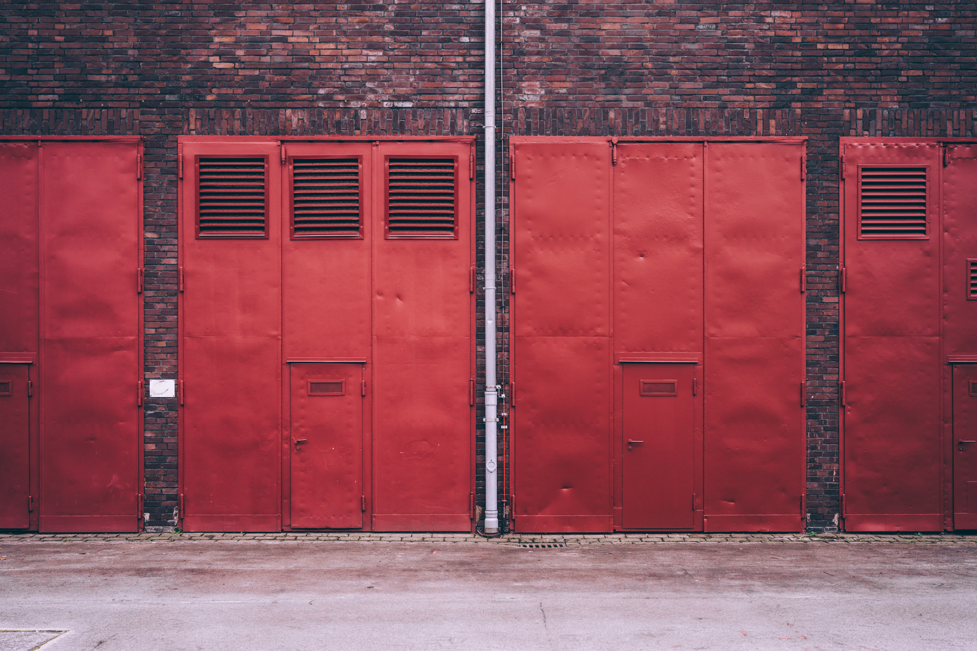 Rote Stahltüren mit Lüftungsgittern an einem Backsteingebäude des Unesco-Welterbes Zollverein in Essen