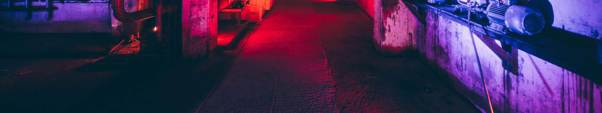 Blick in die ehemalige, mit rotem und violettem Neonlicht beleuchtete Fabrikanlage des heutigen Unesco-Welterbes Zollverein in Essen. © Tourismus NRW e.V./Johannes Höhn