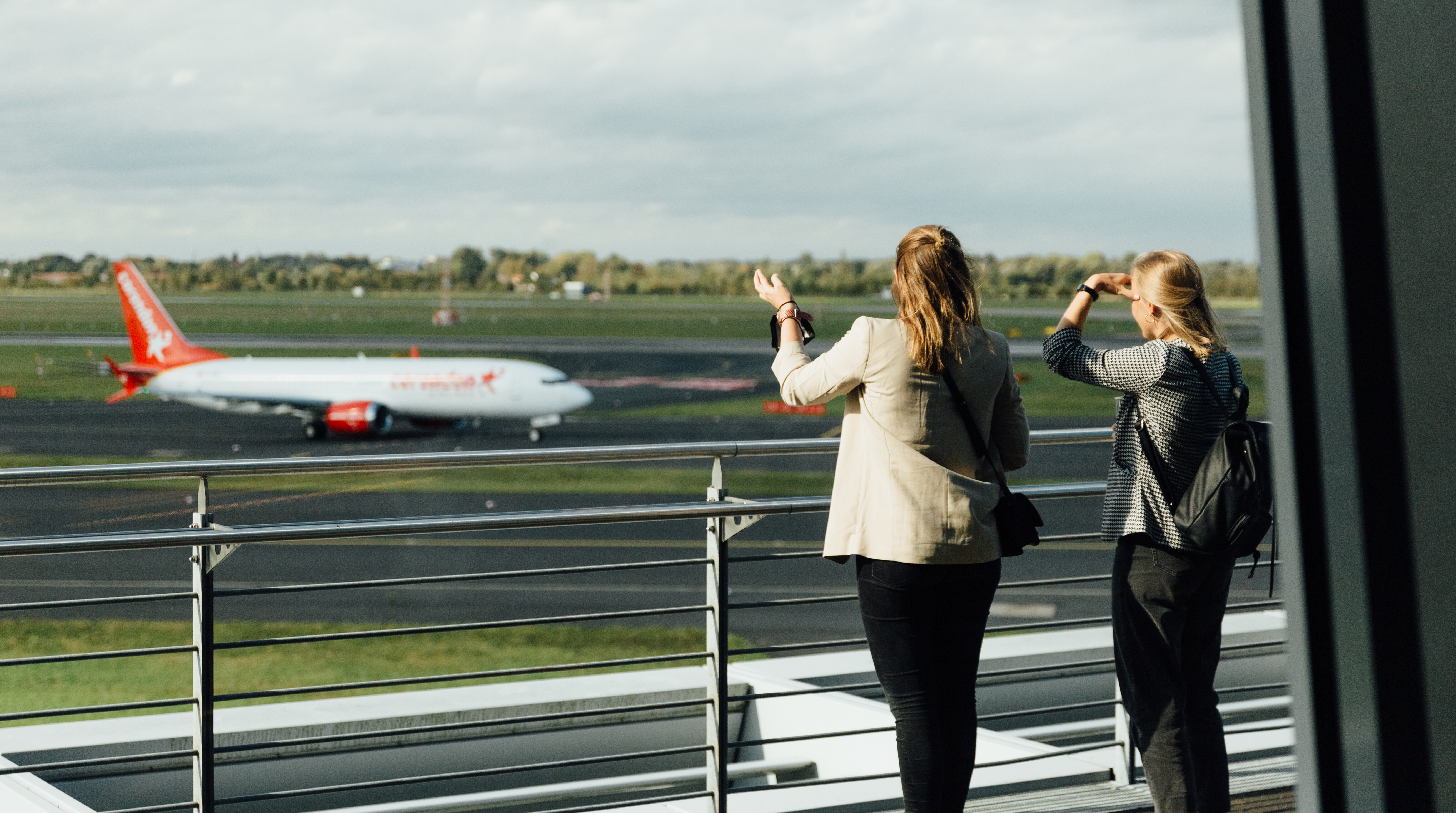 Zwei Frauen beim Fachkongress Smart Destination des Tourismus NRW schauen auf das Rollfeld am Düsseldorfer Flughafen.