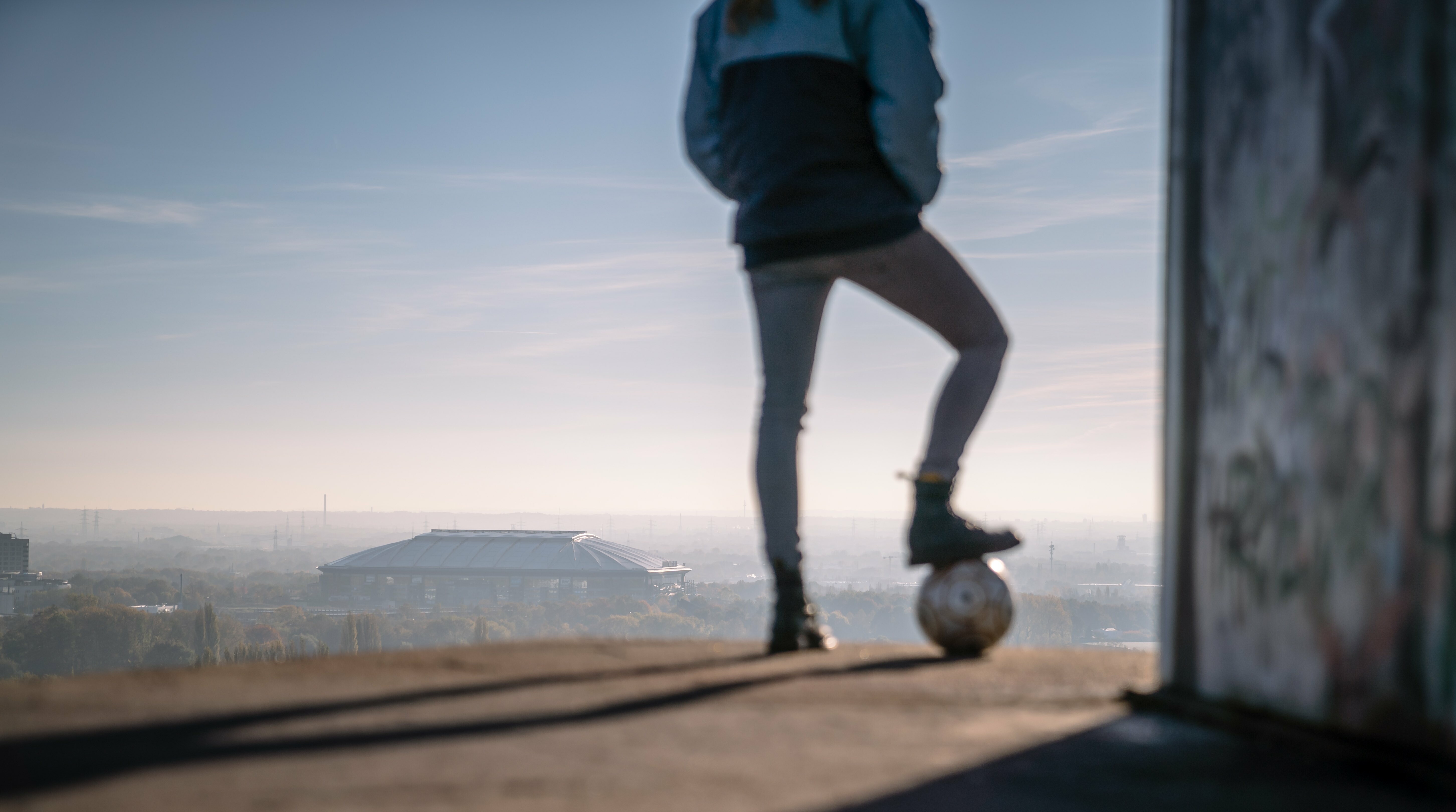Eine Person mit einem Fußball blickt auf Halde Rungenberg in Gelsenkirchen