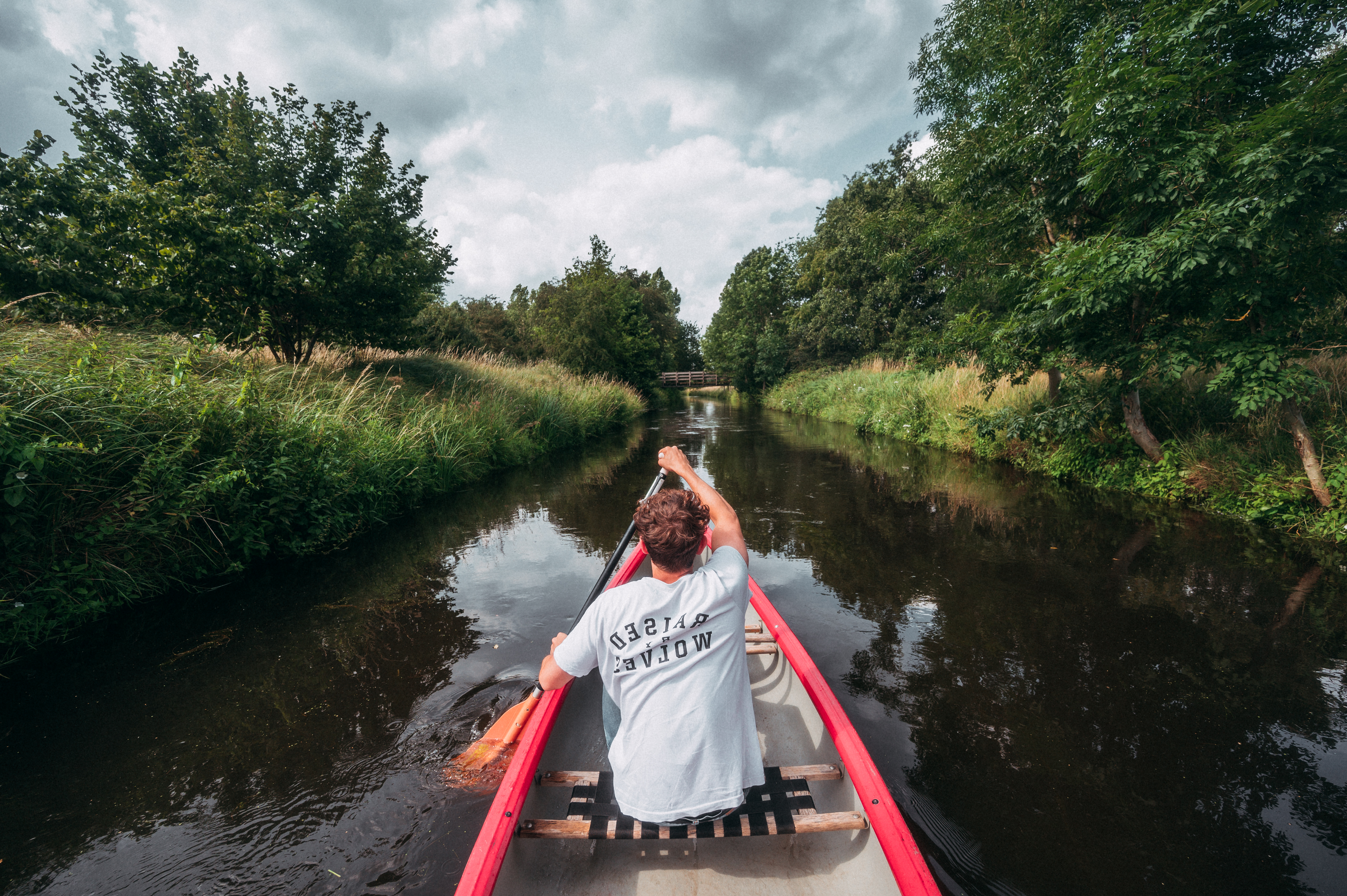 Ein Mensch paddelt auf der Niers am Niederrhein. Die Flussauen sind dicht mit Gräsern und Bäumen bewachsen. © Tourismus NRW e.V./Johannes Höhn