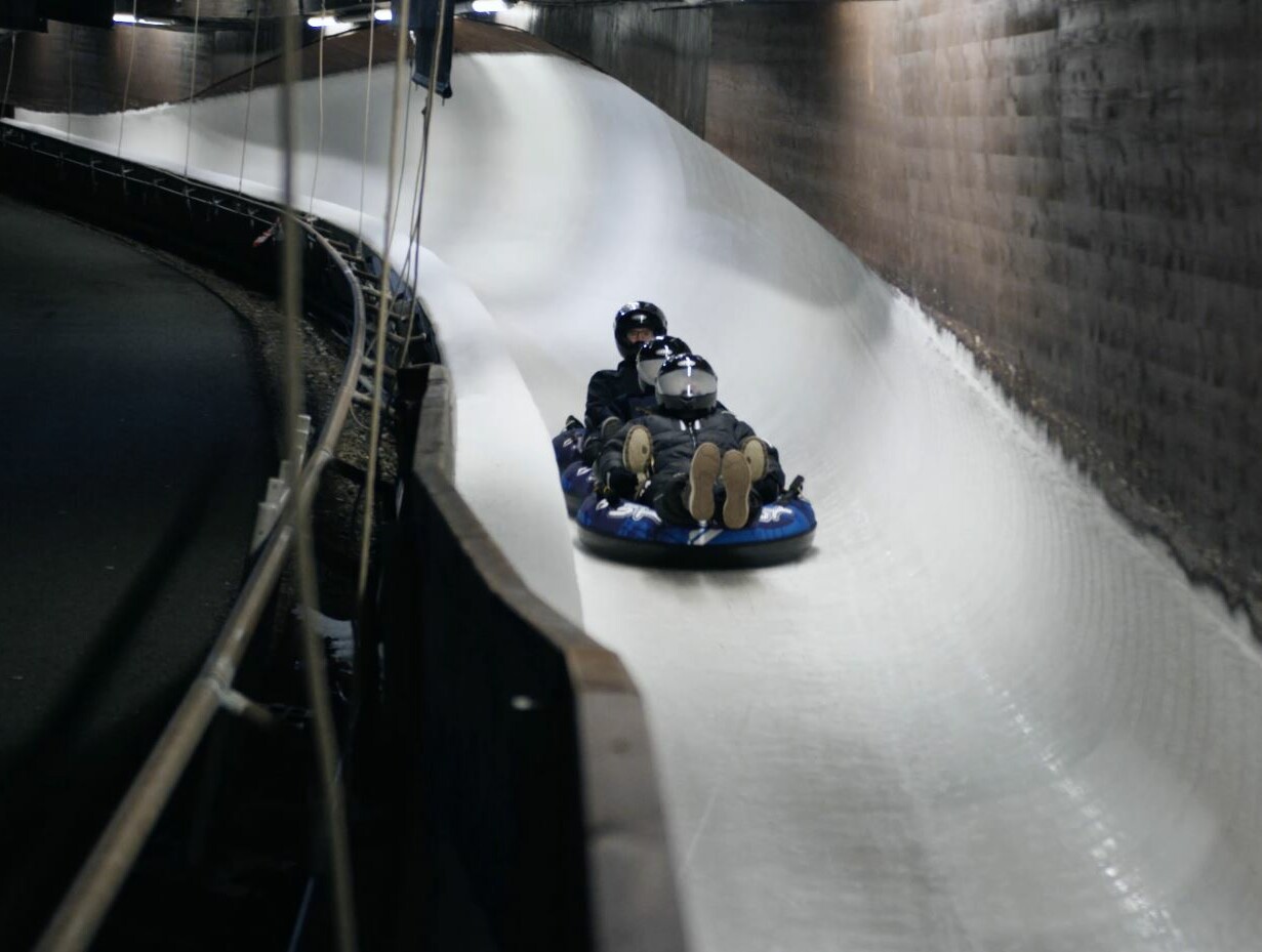 Mehrere Personen rodeln auf IceTubes durch den Eiskanal in Winterberg.