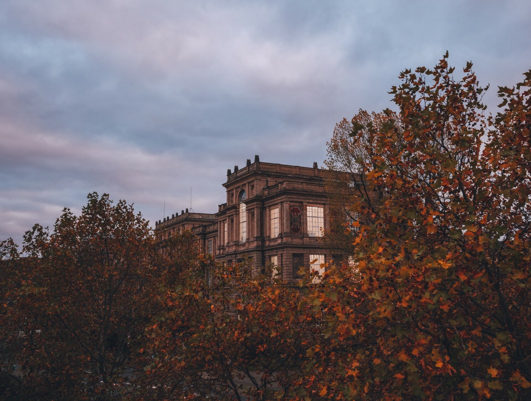 Das historische Gebäude der Kunstakademie Düsseldorf hinter herbstlich gefärbten Bäumen